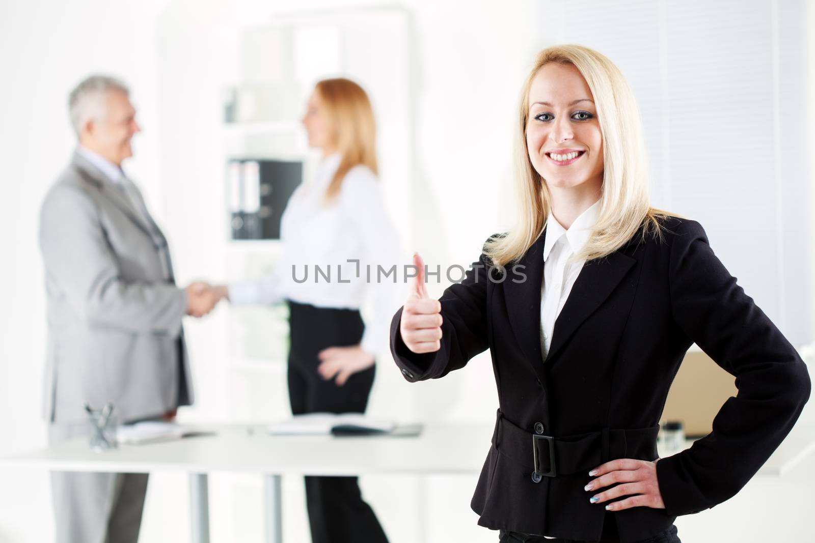 Happy Beautiful young businesswoman showing thumbs up in the office. Looking at camera. Selective Focus.