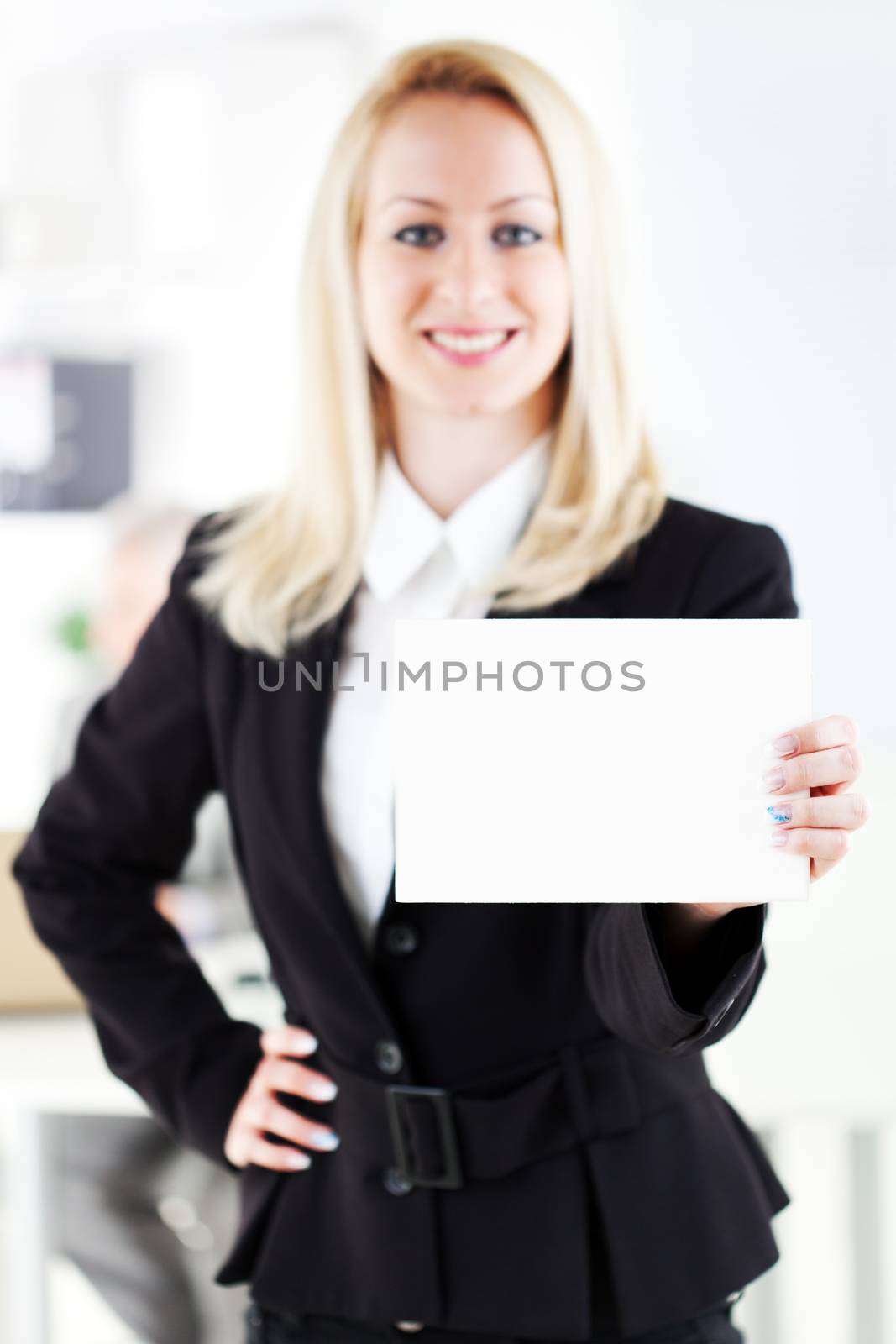 Beautiful young businesswoman holding Blank business card in the office. Looking at camera. Selective Focus. Focus on card.