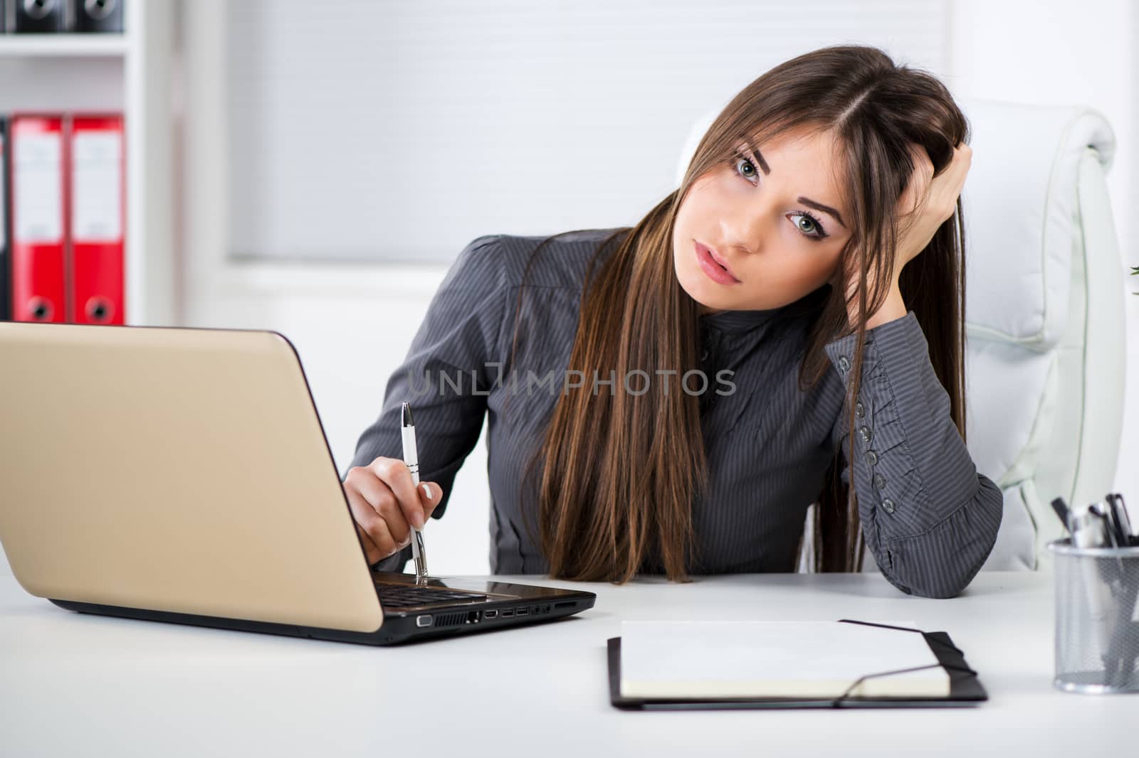 Worried Businesswoman in the office, sitting and thinking about problems. Looking at camera.