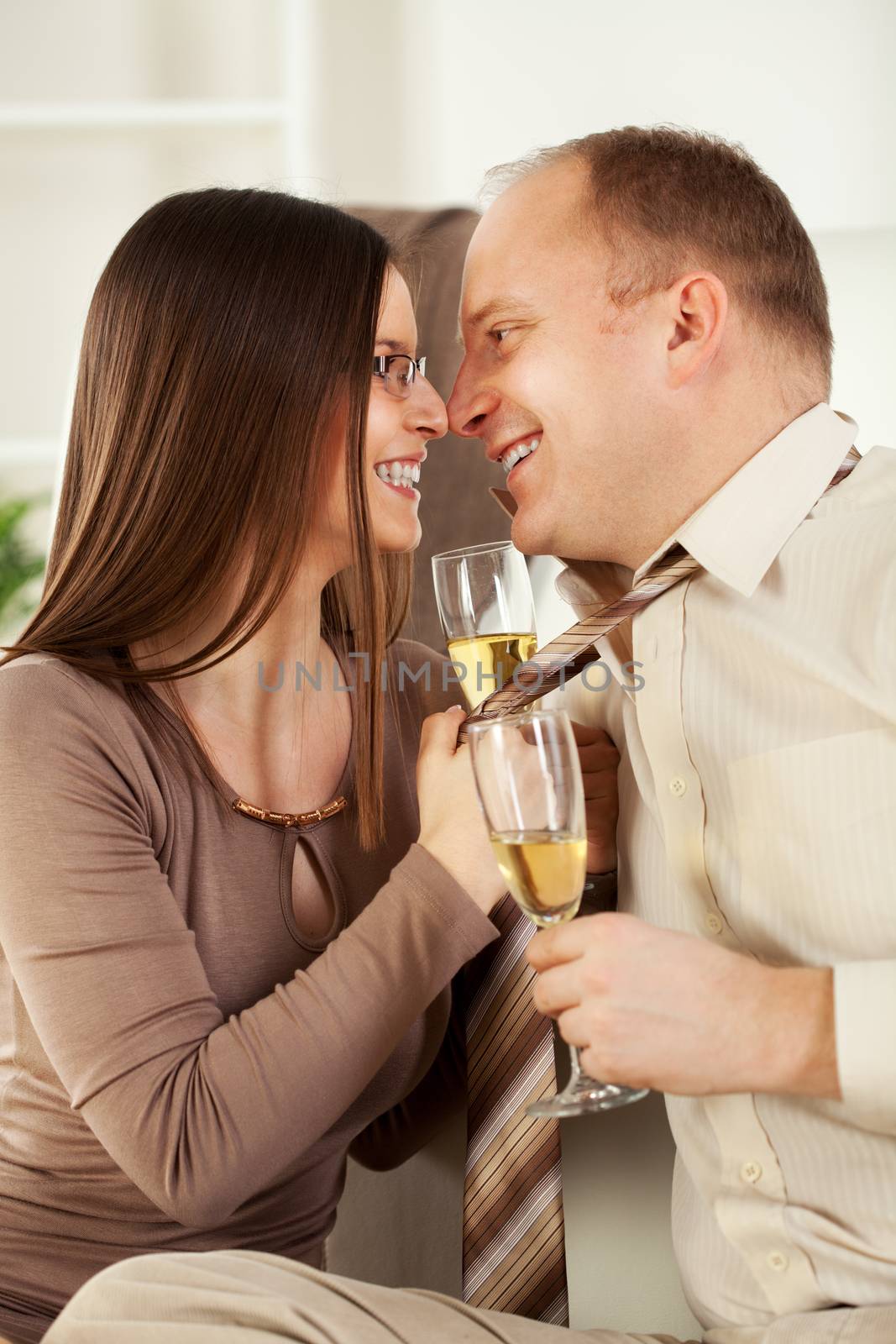 Happy Young woman pulling guy's tie and drinking  champagne.
