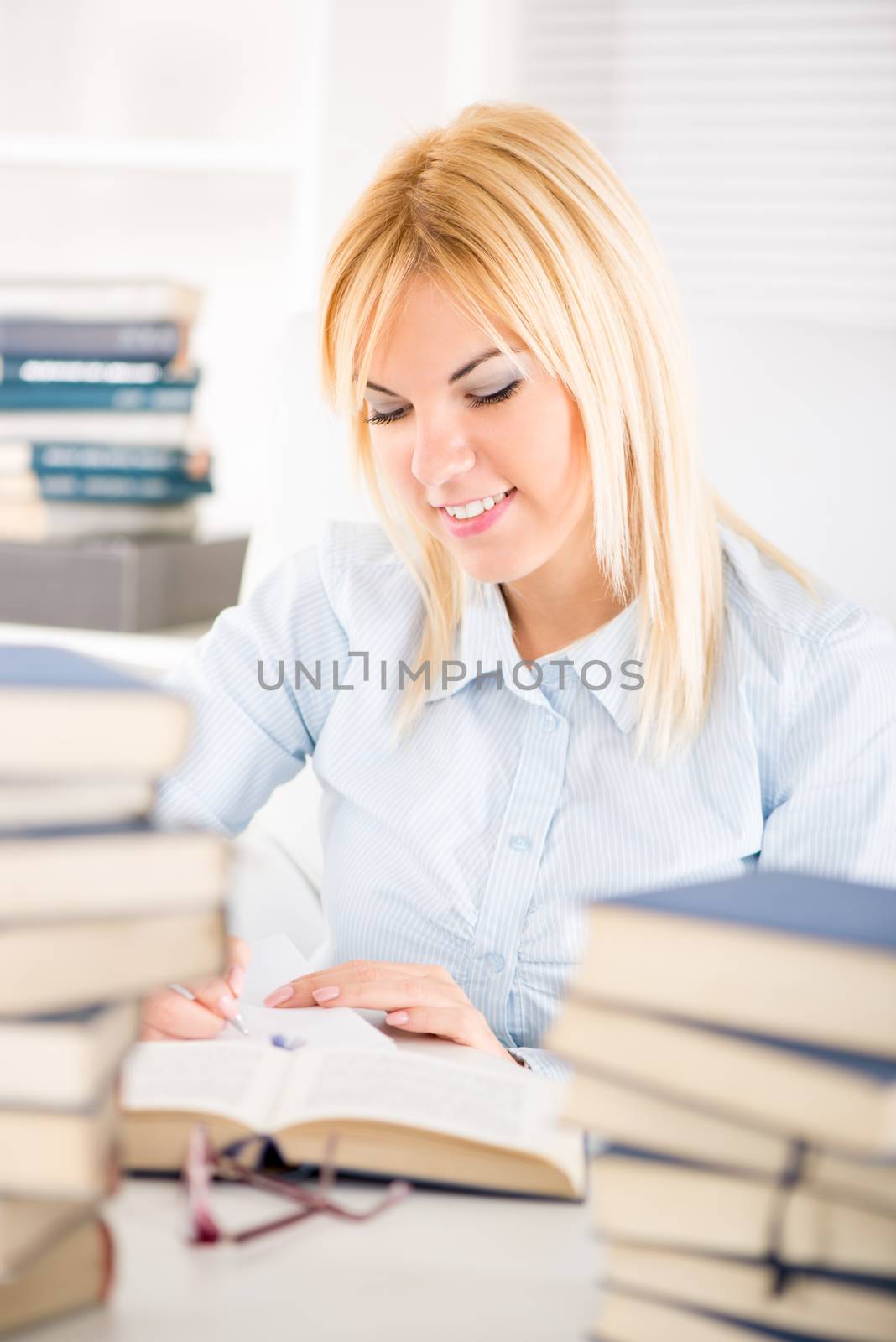 Beautiful Student girl sitting with many books and marking text what need to learn.