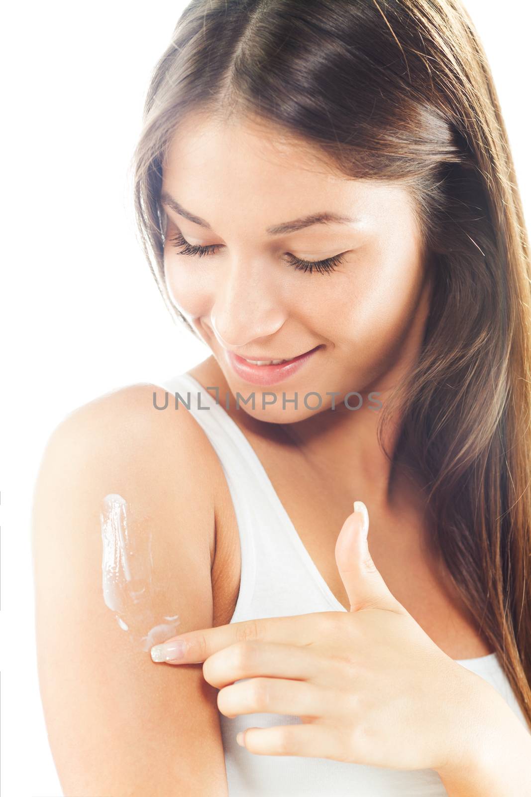 Beautiful young woman applying body lotion.