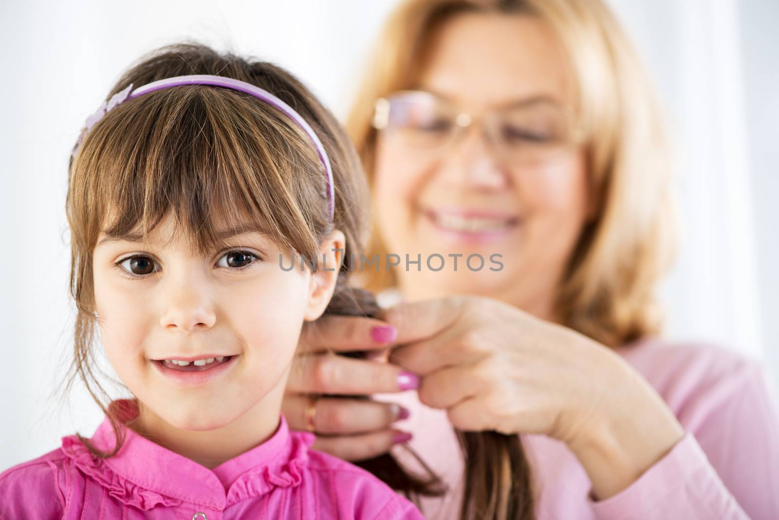 Beautiful Grandmother making Braid to cute granddaughter 