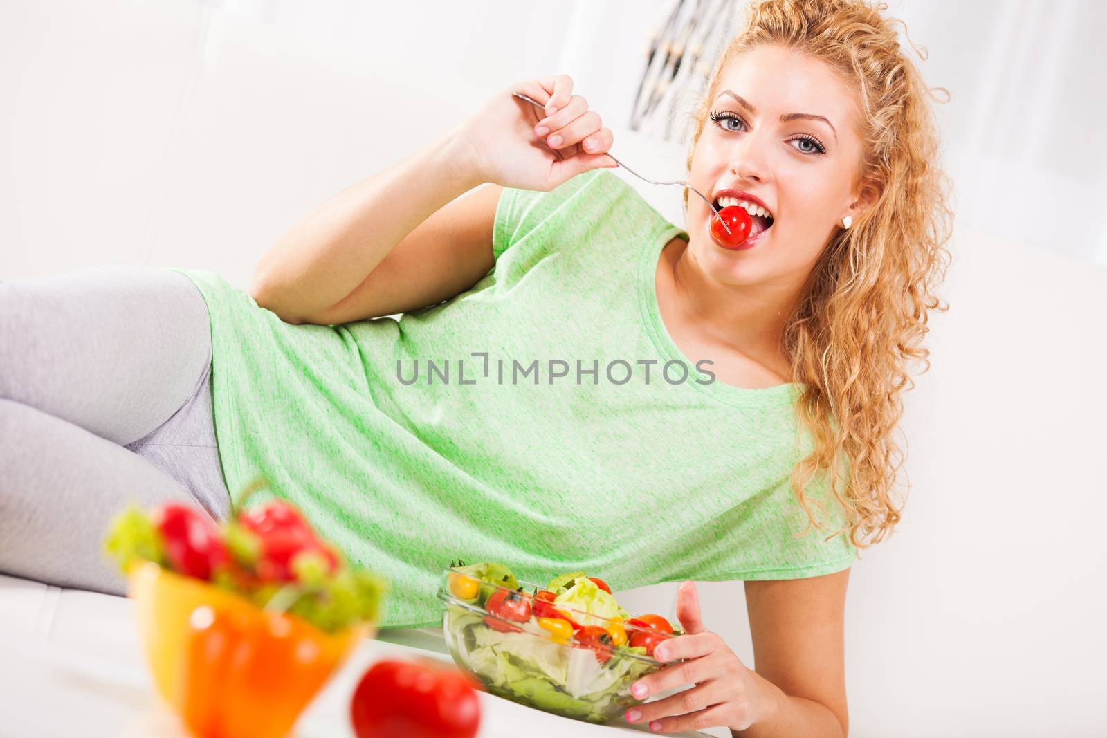 Beautiful young woman eating small tomato with fork