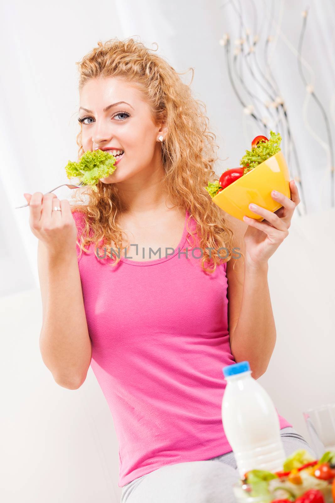 Beautiful young woman eating salad 