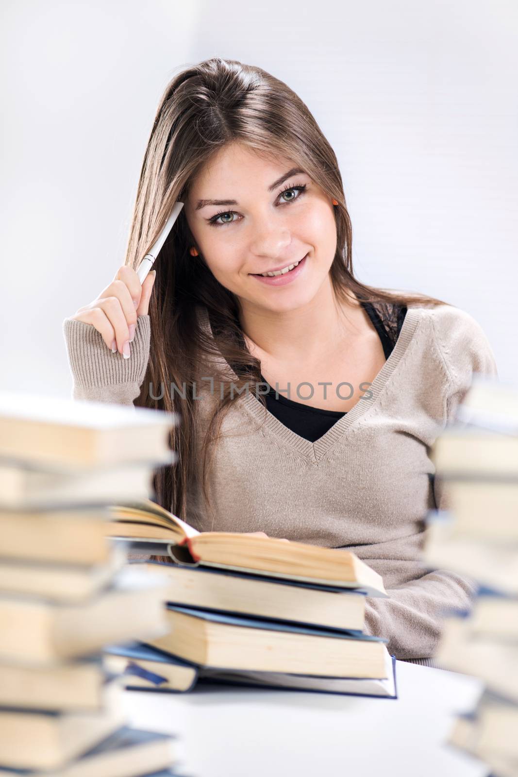 Beautiful Student girl learning and thinking between many books. Selective focus.