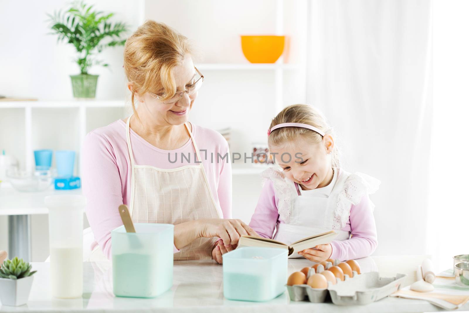Grandmother and granddaughter in a kitchen.  by MilanMarkovic78