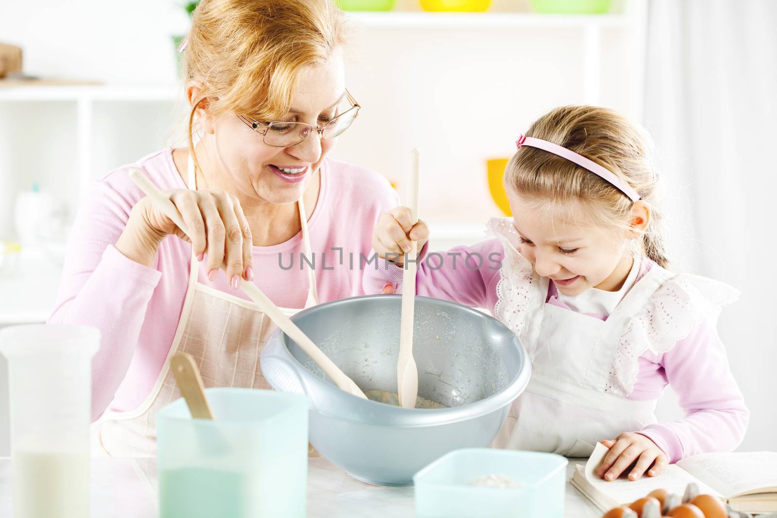 Beautiful happy grandmother learning her granddaughter Baking in a kitchen. 