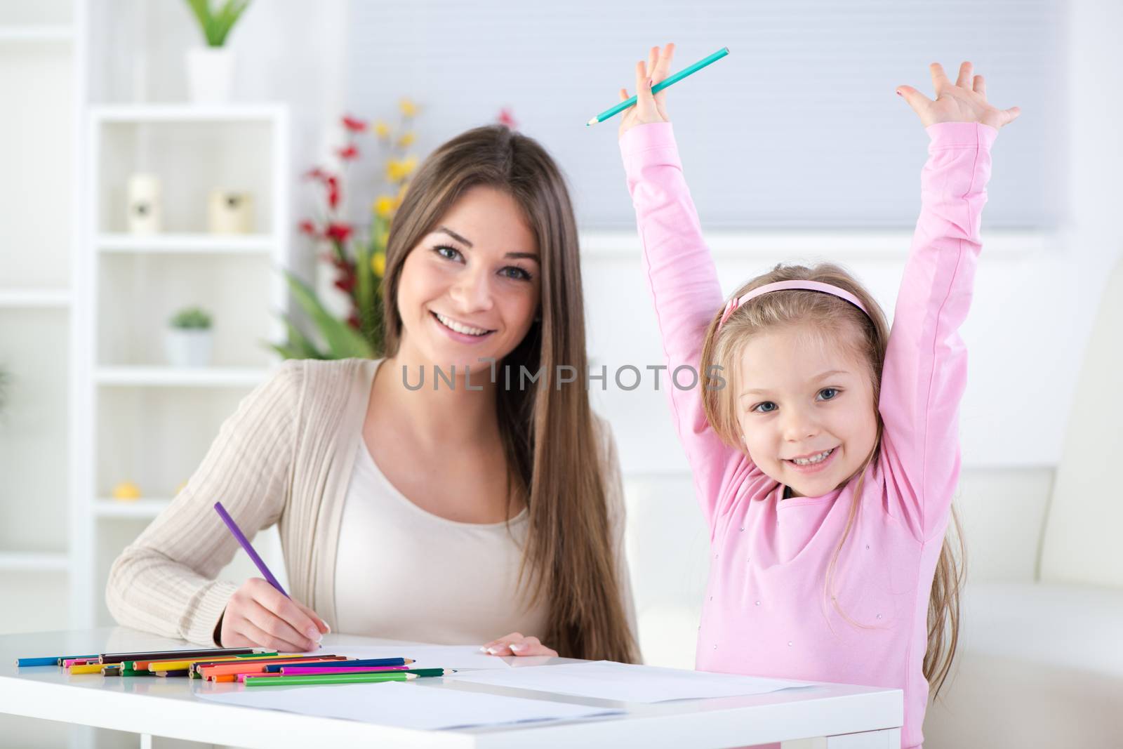 Mother and daughter at home. They drawing with colored pencils.