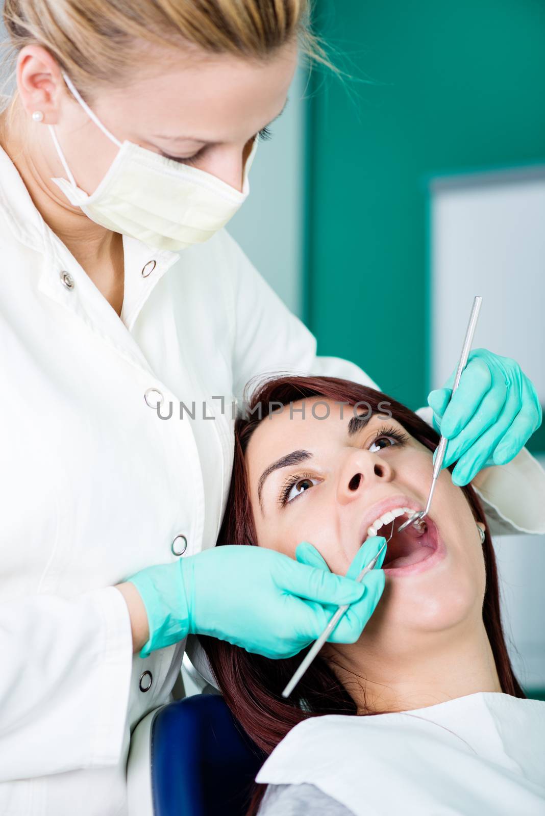 Young female dentist checking dental hygiene on patient in the office.