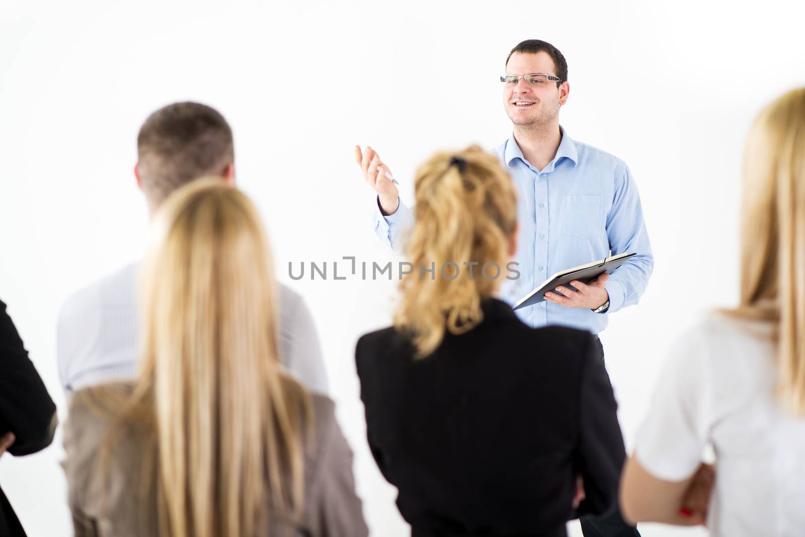 Friendly business man explaining plan of work in front of coworkers. The team is listening.