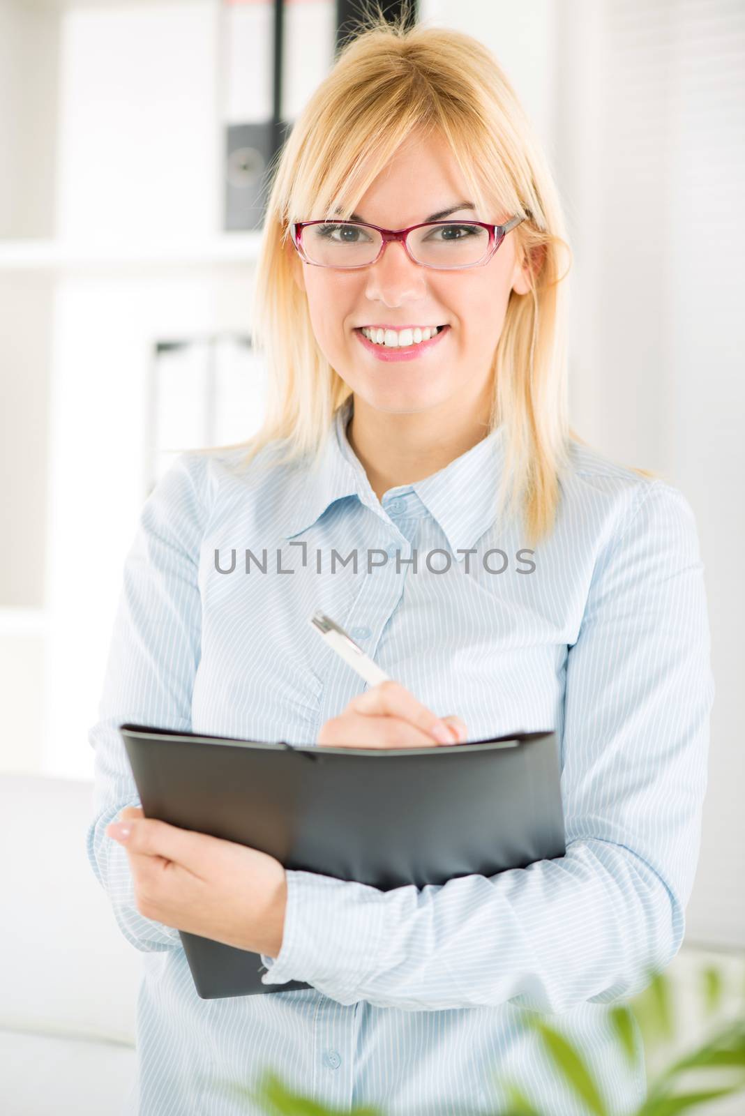 Beautiful Businesswoman with glasses standing in the office and looking at camera.