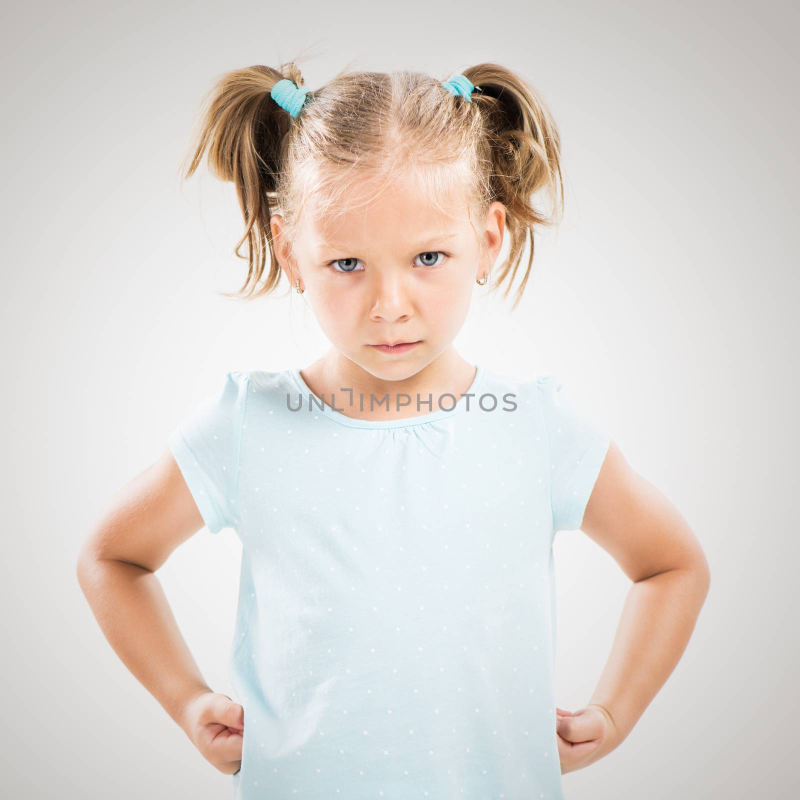Cute angry little girl standing with hands on hips.