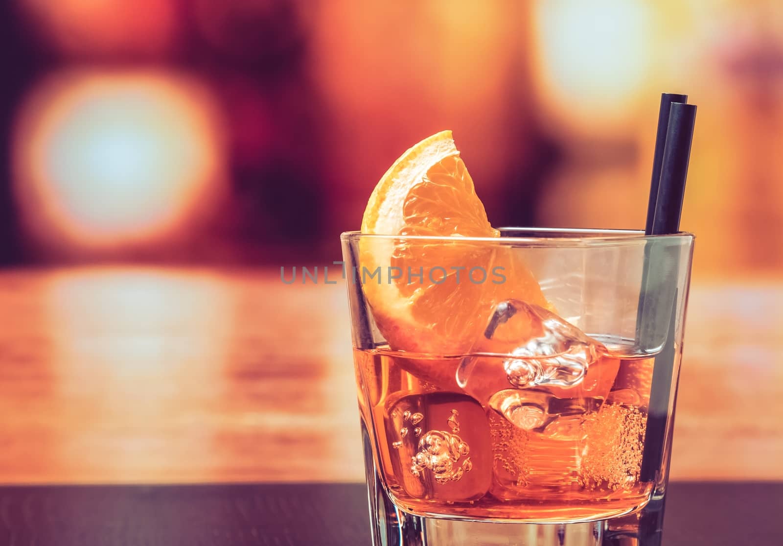 glass of spritz aperitif aperol cocktail with orange slices and ice cubes on bar table, vintage atmosphere background, lounge bar concept