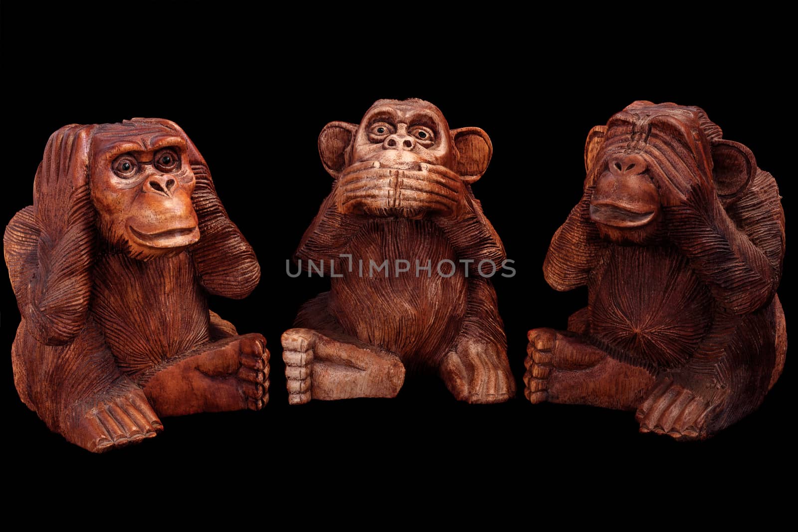 Three wise monkeys. Figurines of wood on a black background.