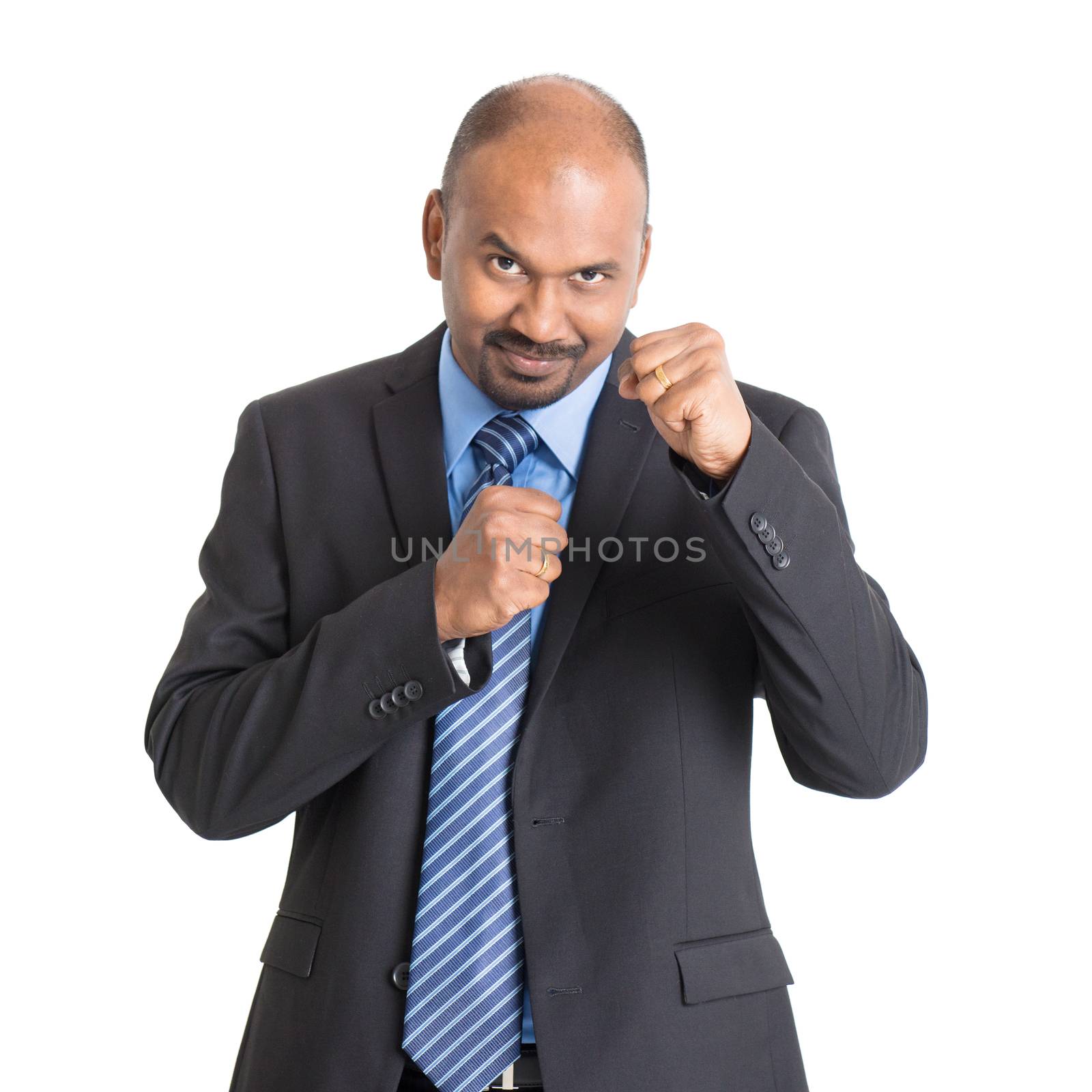 Mature Indian businessman in kungfu fighting mood, standing on plain background with shadow.