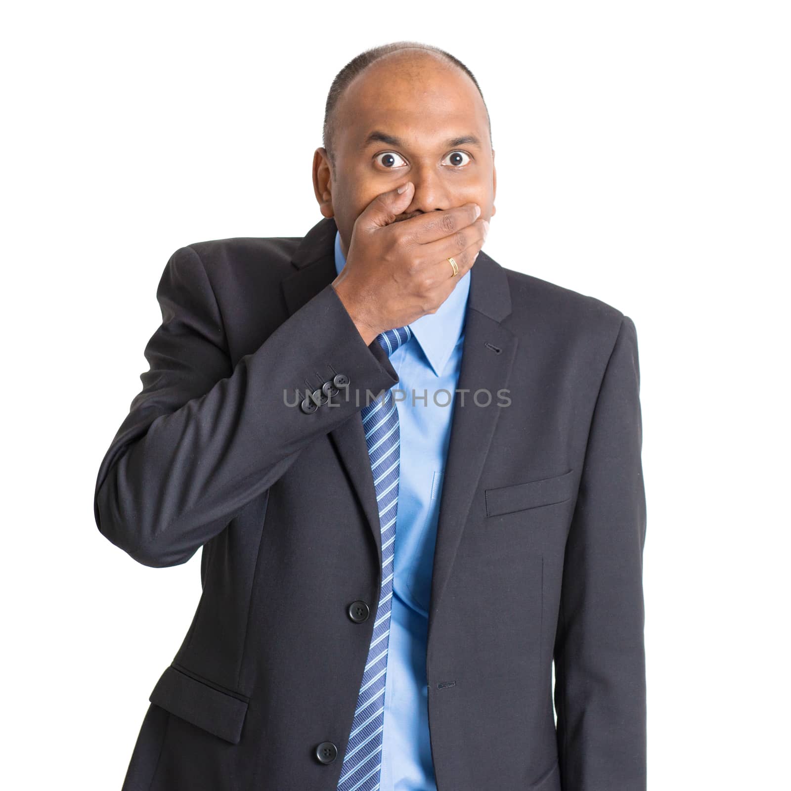 Portrait of shocked mature Indian businessman covered mouth, standing on plain background with shadow.