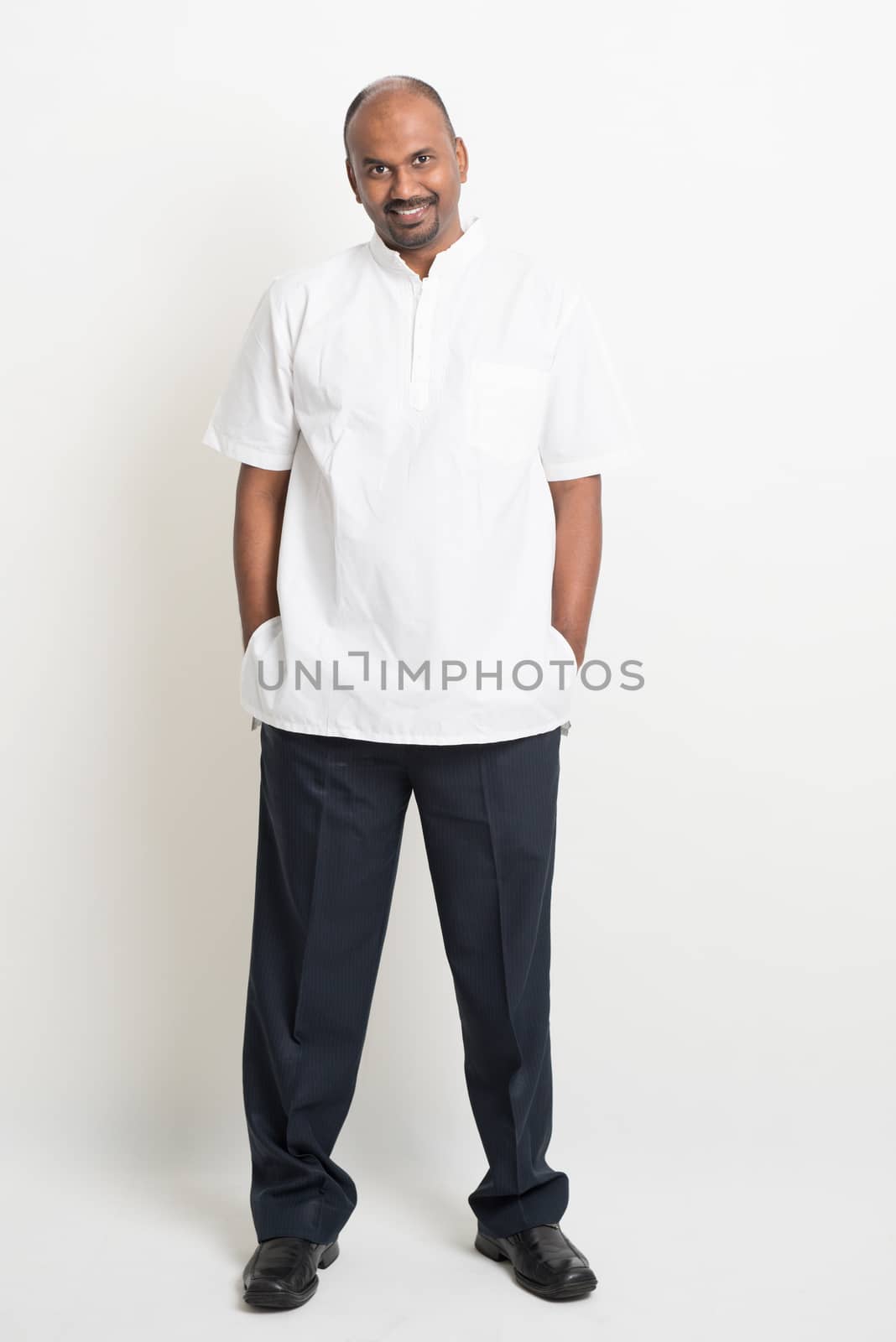 Full body casual mature Indian business people smiling and standing on plain background.