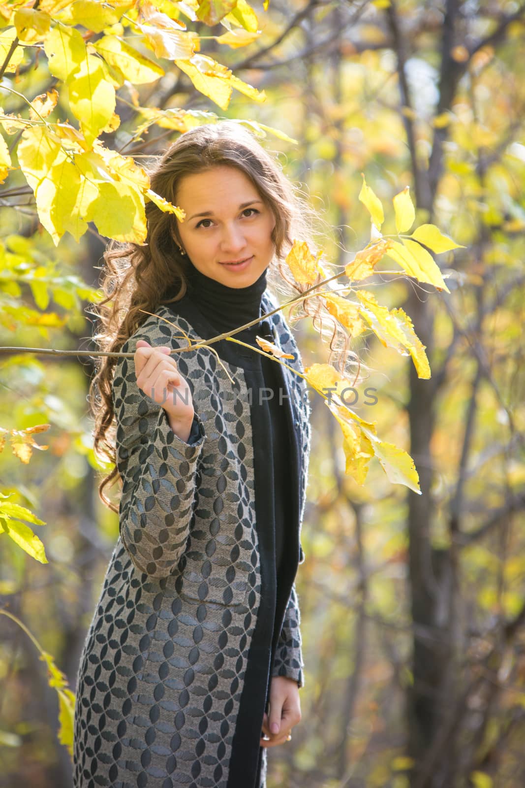 Cute young girl holding a twig with yellow leaves against the backdrop of autumn yellow forest by Madhourse