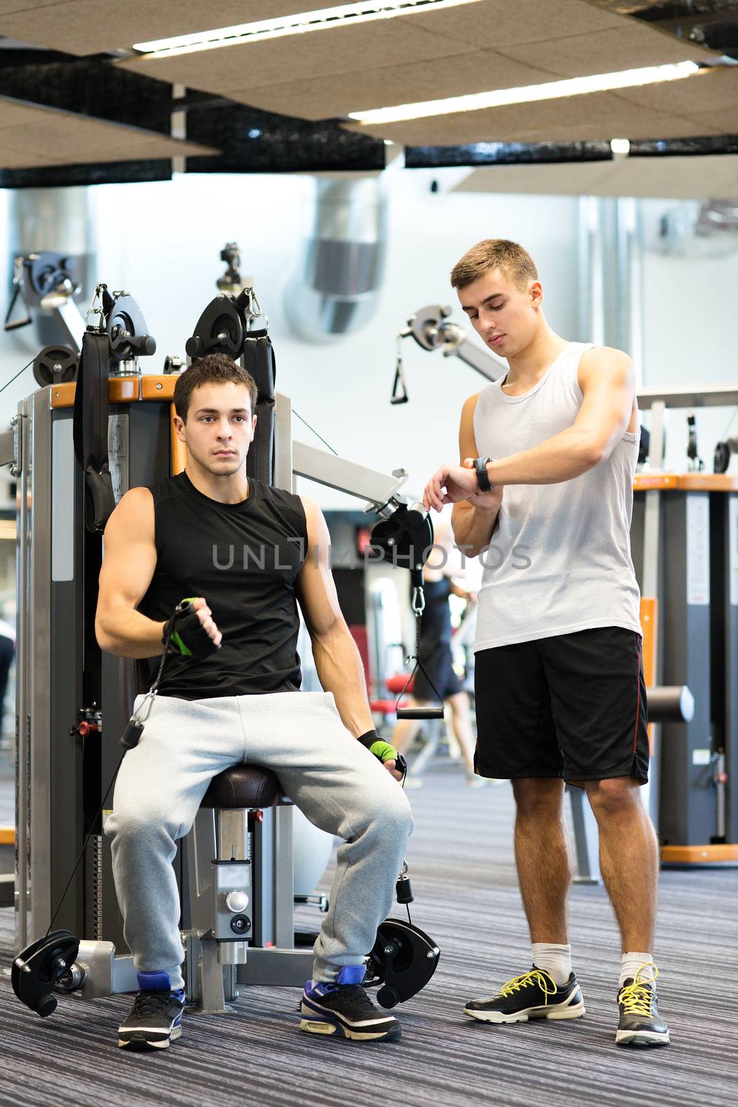 sport, fitness, equipment, lifestyle and people concept - men exercising on gym machine