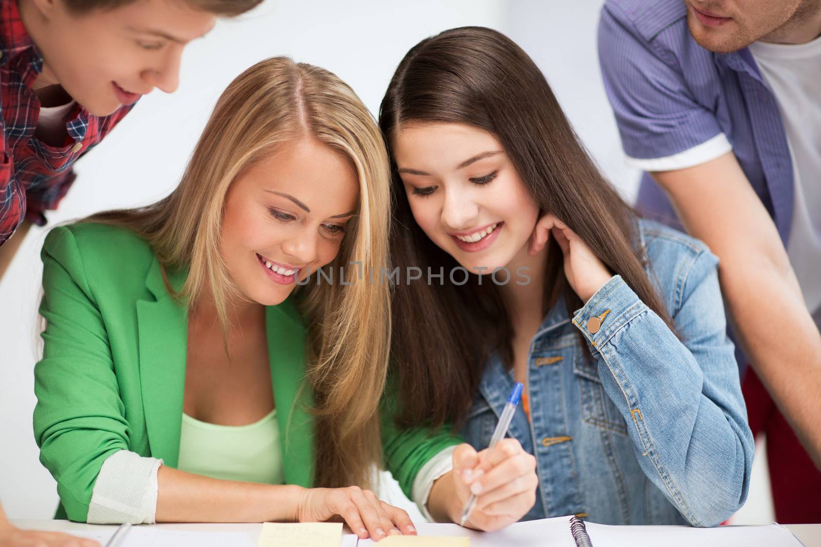 education concept - students pointing at notebook at school