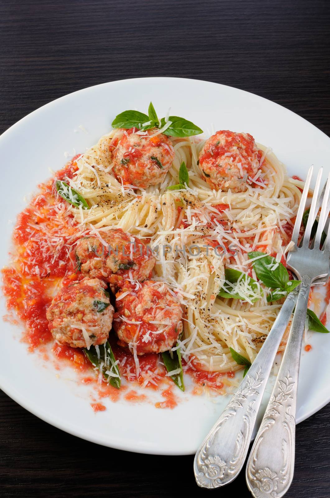 Pasta in tomato gravy with meatballs sprinkled Parmesan and basil