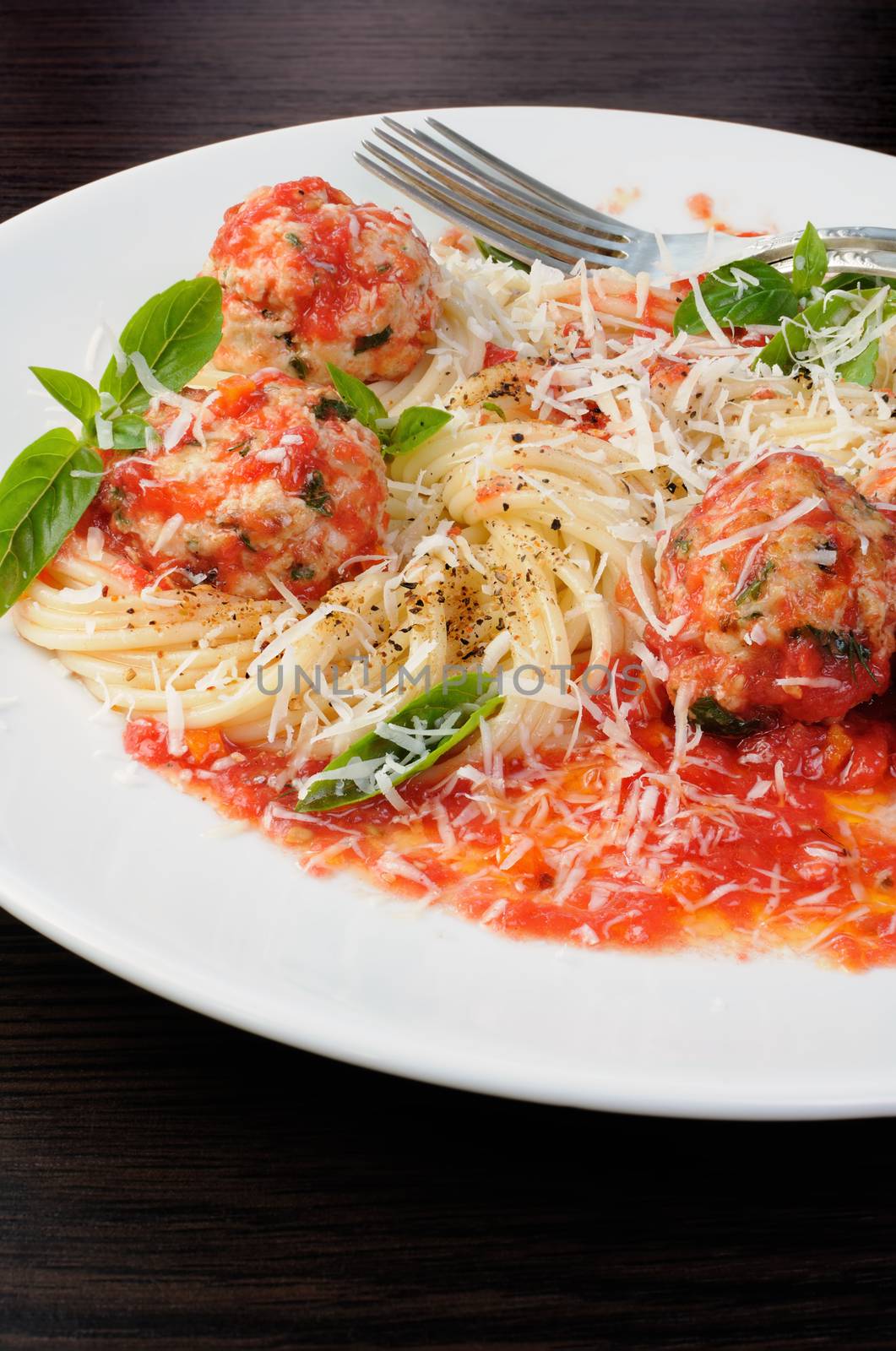 Pasta in tomato gravy with meatballs sprinkled Parmesan and basil