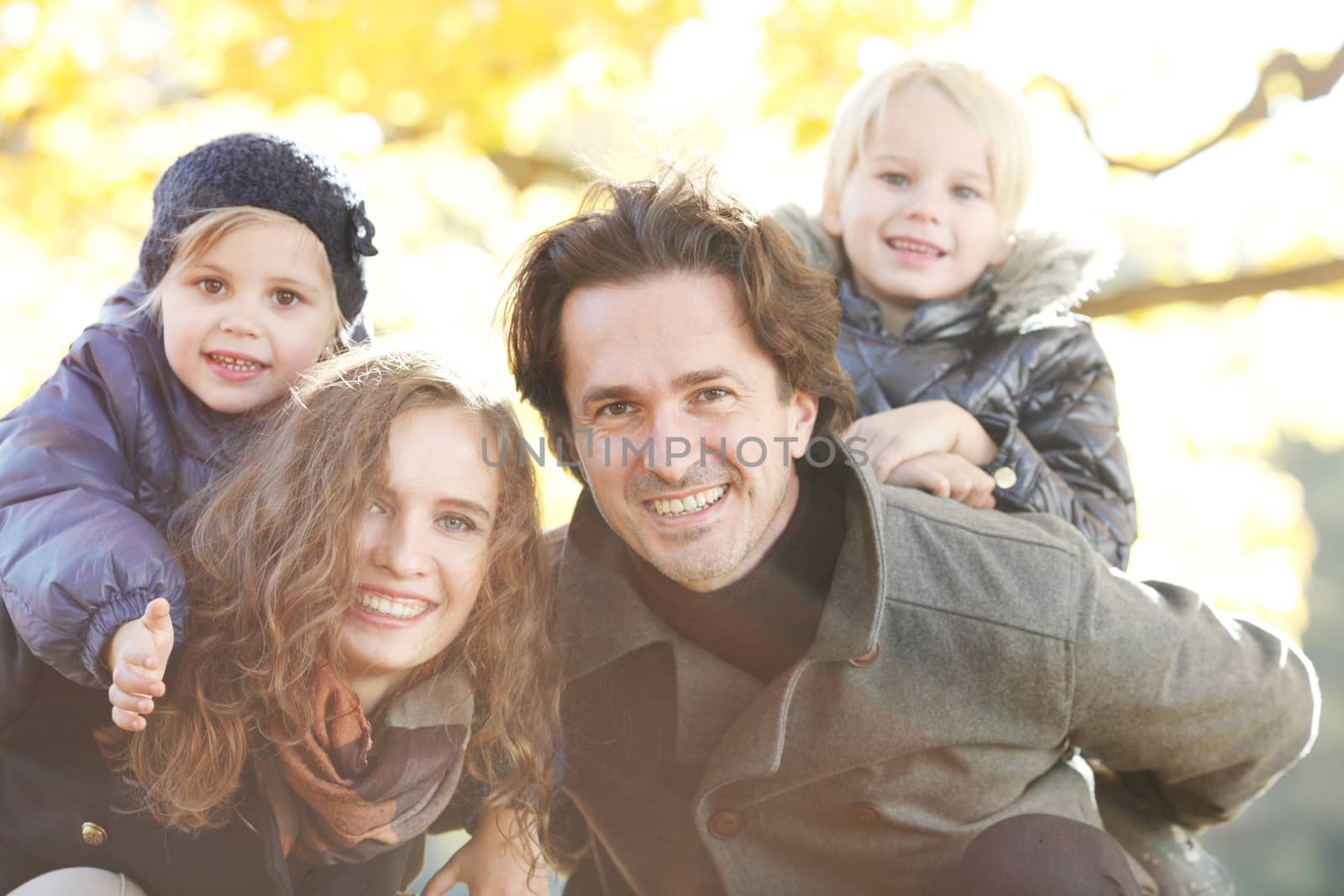 Portrait of a happy family in autumn park with maple leaves