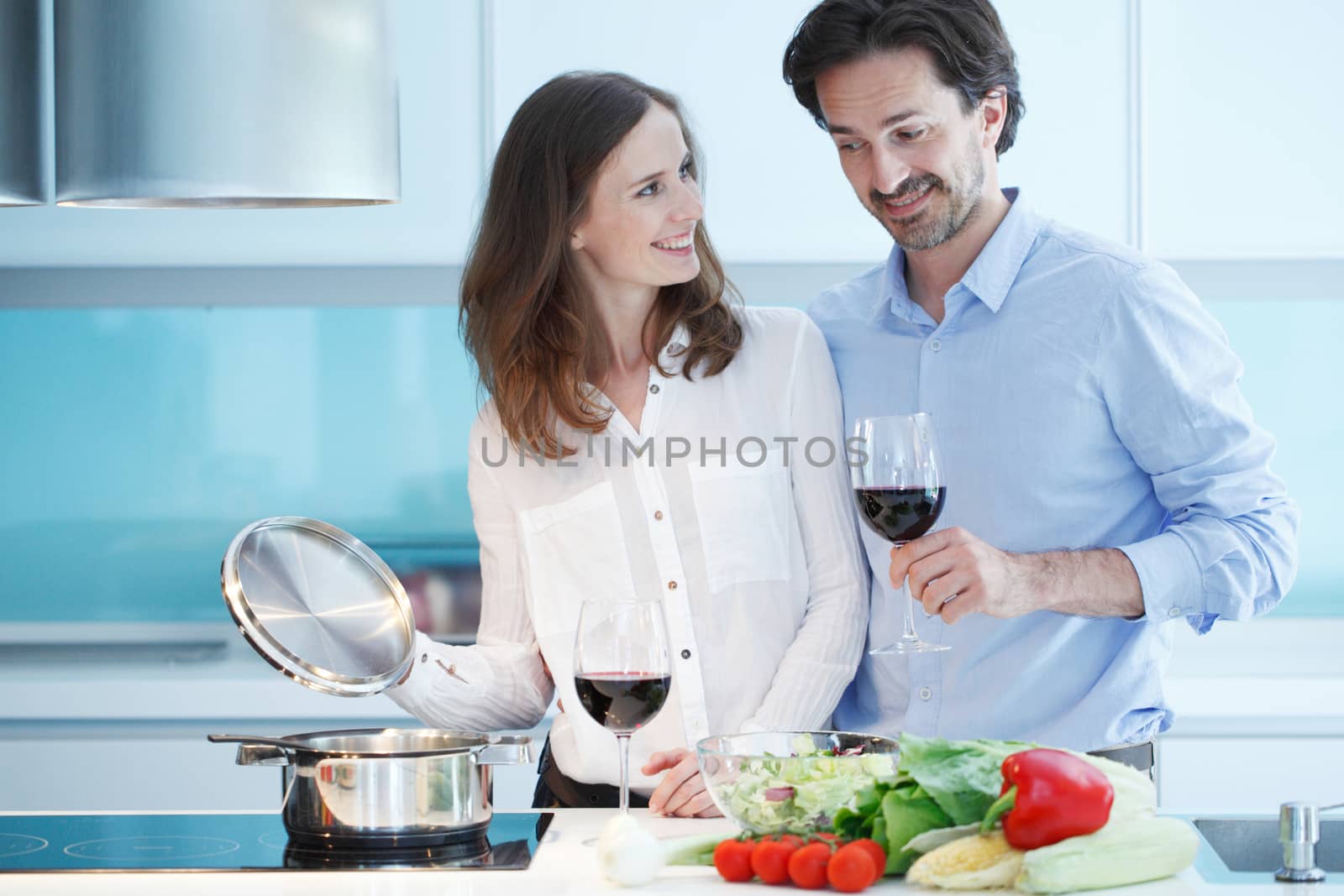 Portrait of a couple having a glass of red wine while cooking dinner