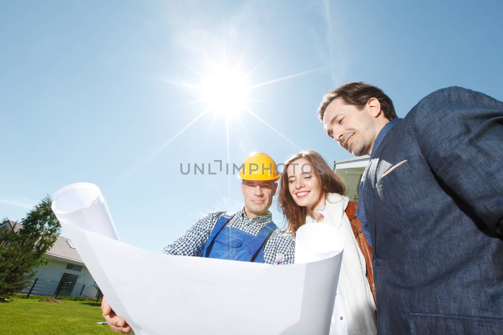 foreman shows house design plans to a young couple outdoors