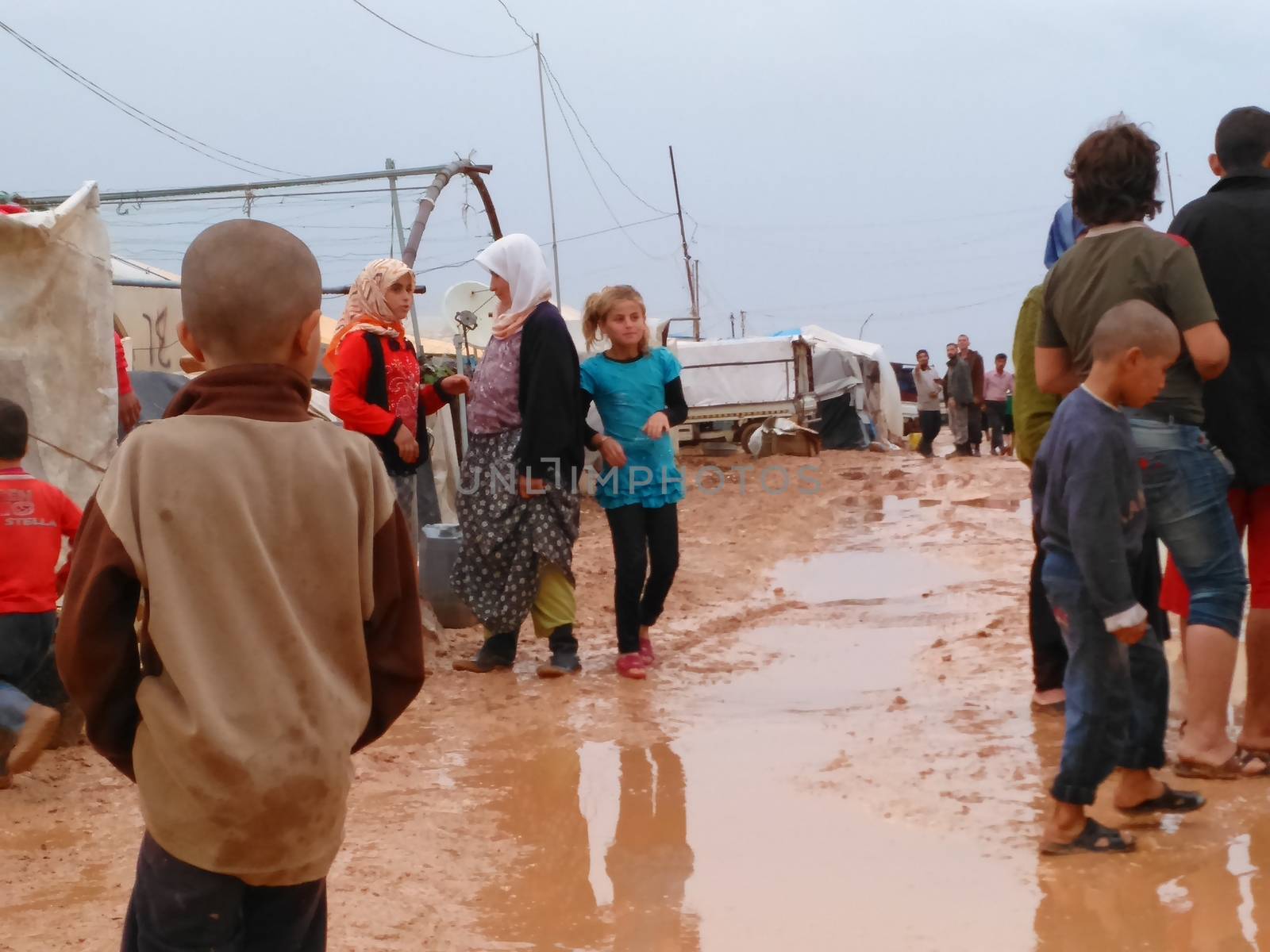 SYRIA, Azaz : Adults and children stand, feet in the mud, in Bab al-Salameh, a non official refugee camp near Turkish border, near Aza city, northern Aleppo on October 25, 2015. The camp was supposed to be a temporary solution to refugees who flee Syria war to Turkey when it was created in 2012. 