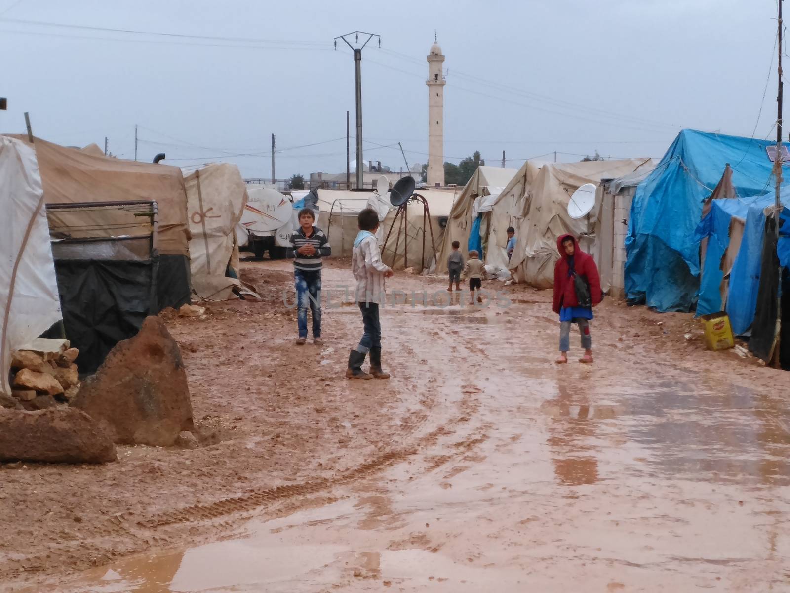 SYRIA, Azaz : Children walk, their feet in the mud, in Bab al-Salameh, a non official refugee camp near Turkish border, near Aza city, northern Aleppo on October 25, 2015. The camp was supposed to be a temporary solution to refugees who flee Syria war to Turkey when it was created in 2012. 