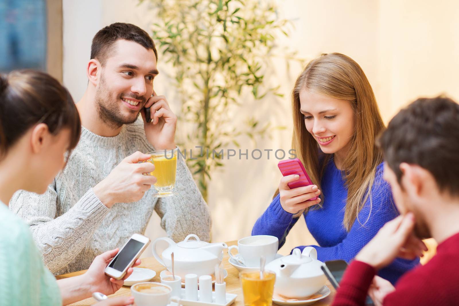 group of friends with smartphones meeting at cafe by dolgachov