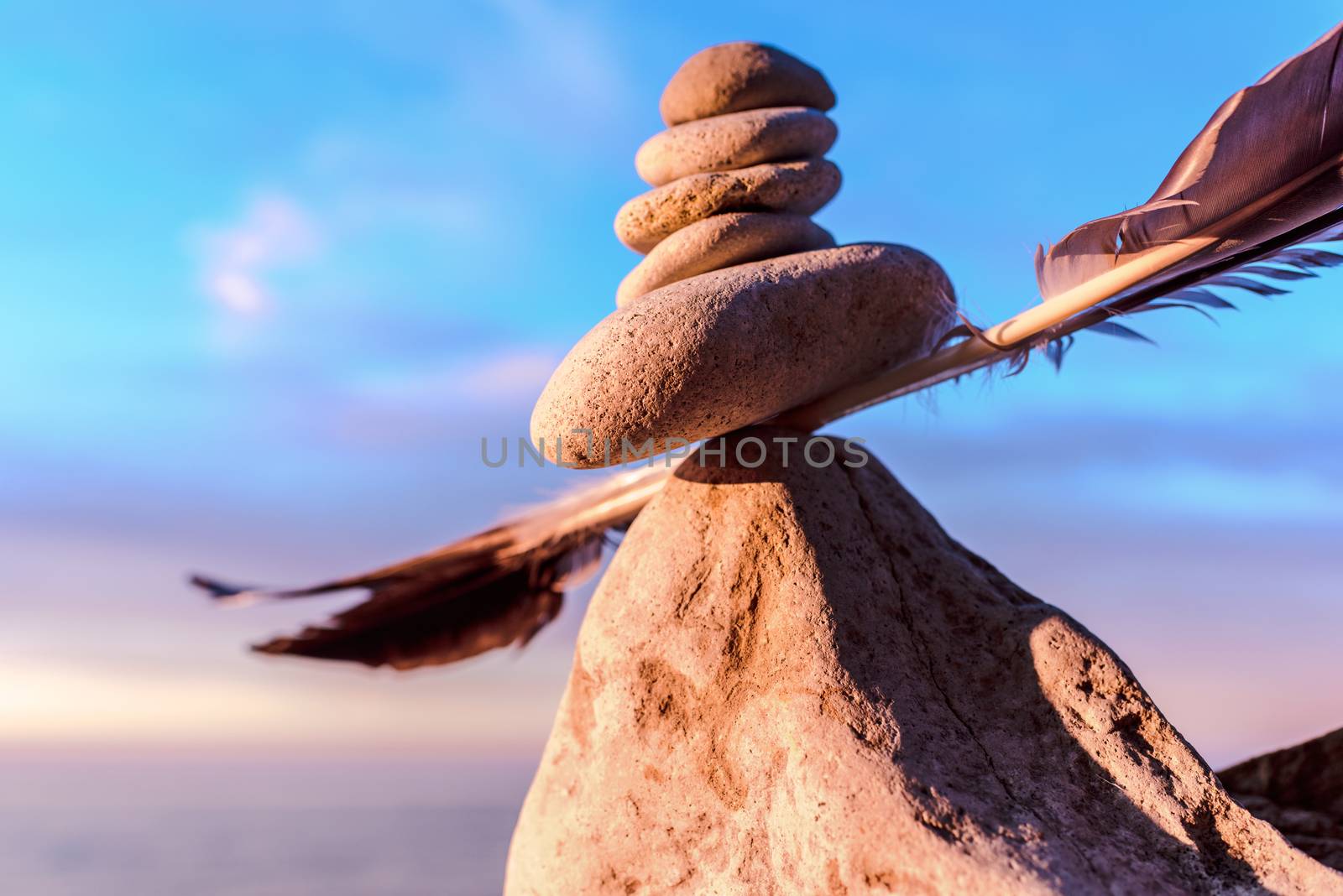 Balancing of stones and feather on the seashore