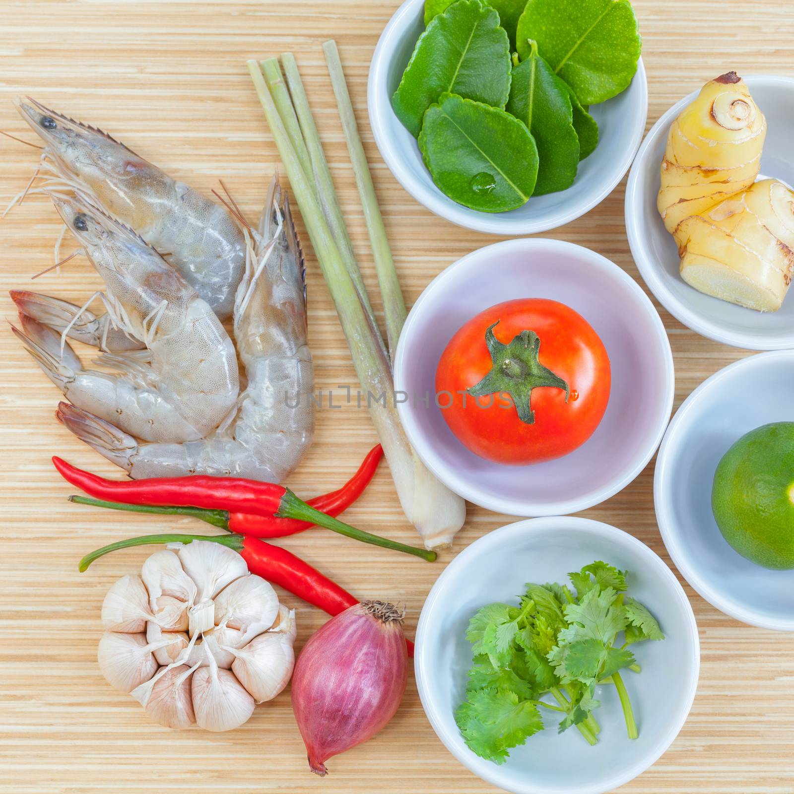 Ingredients of thai spicy soup Tom Yam Kung , big shrimp ,lime, lemon grass and tomato for favourite spicy thai cuisine food with herbs on wooden background.