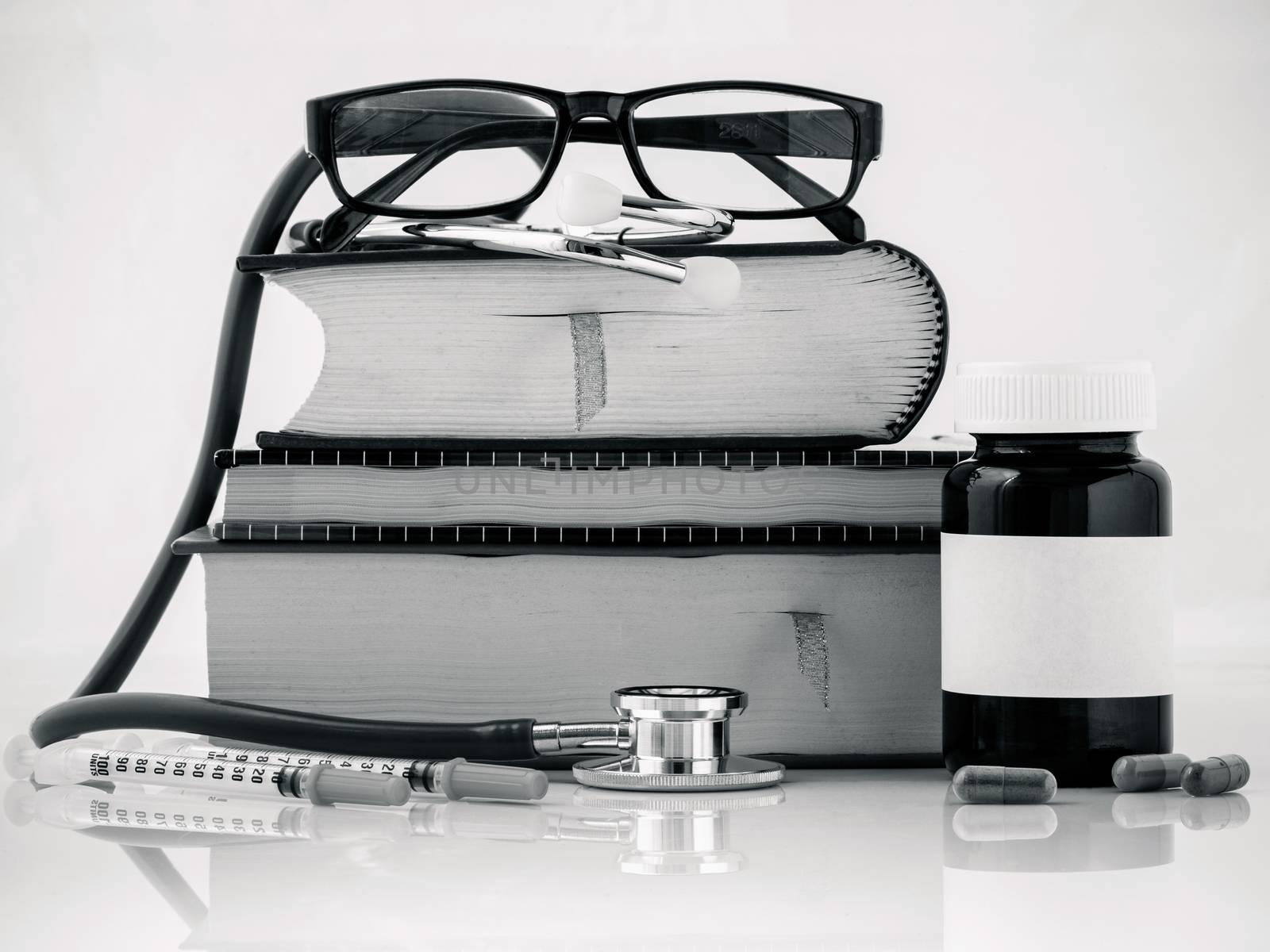 Stethoscope on a textbooks and bottle of pills isolated on white by kerdkanno