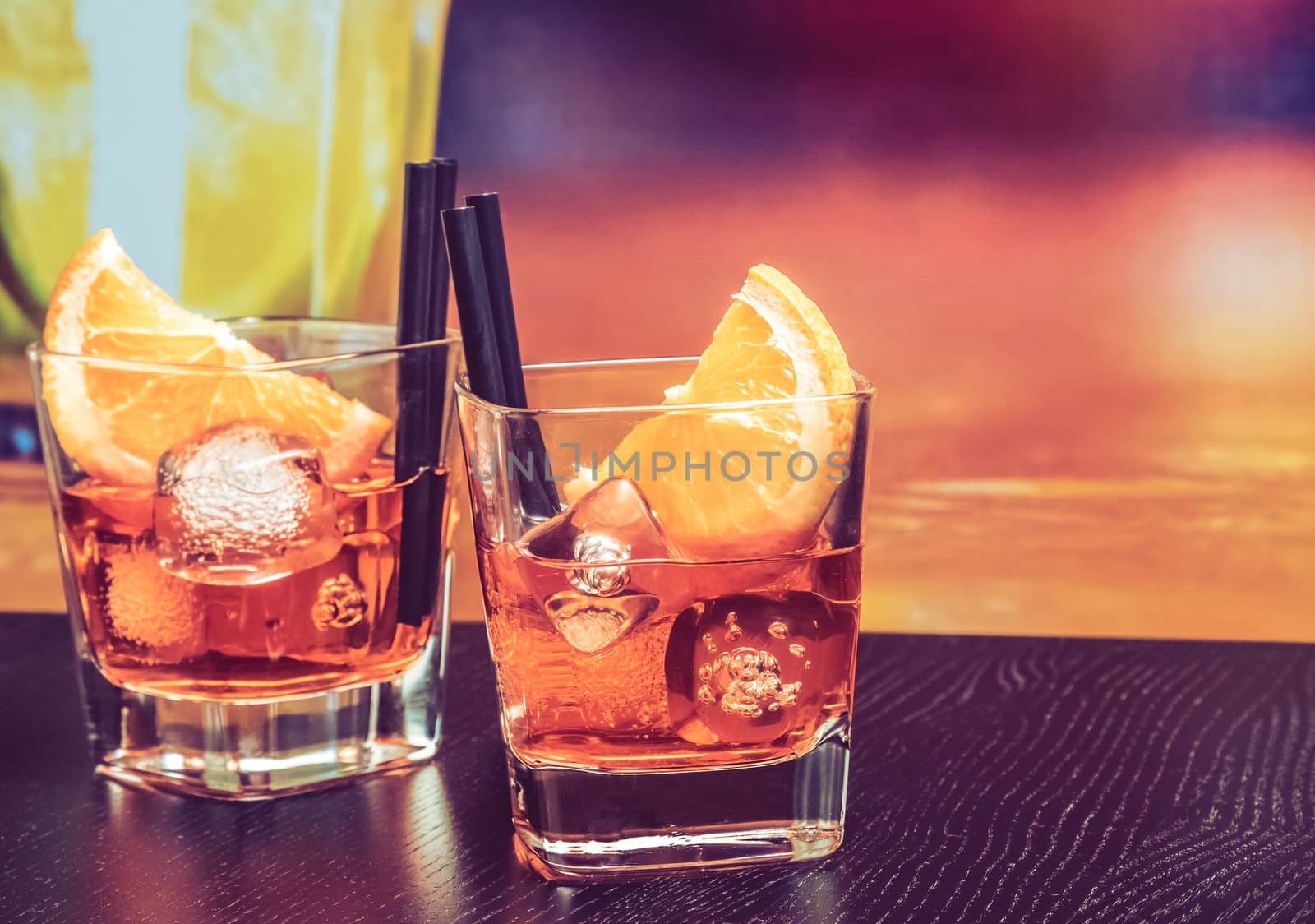 glasses of spritz aperitif aperol cocktail with orange slices and ice cubes on bar table, vintage atmosphere background, lounge bar concept