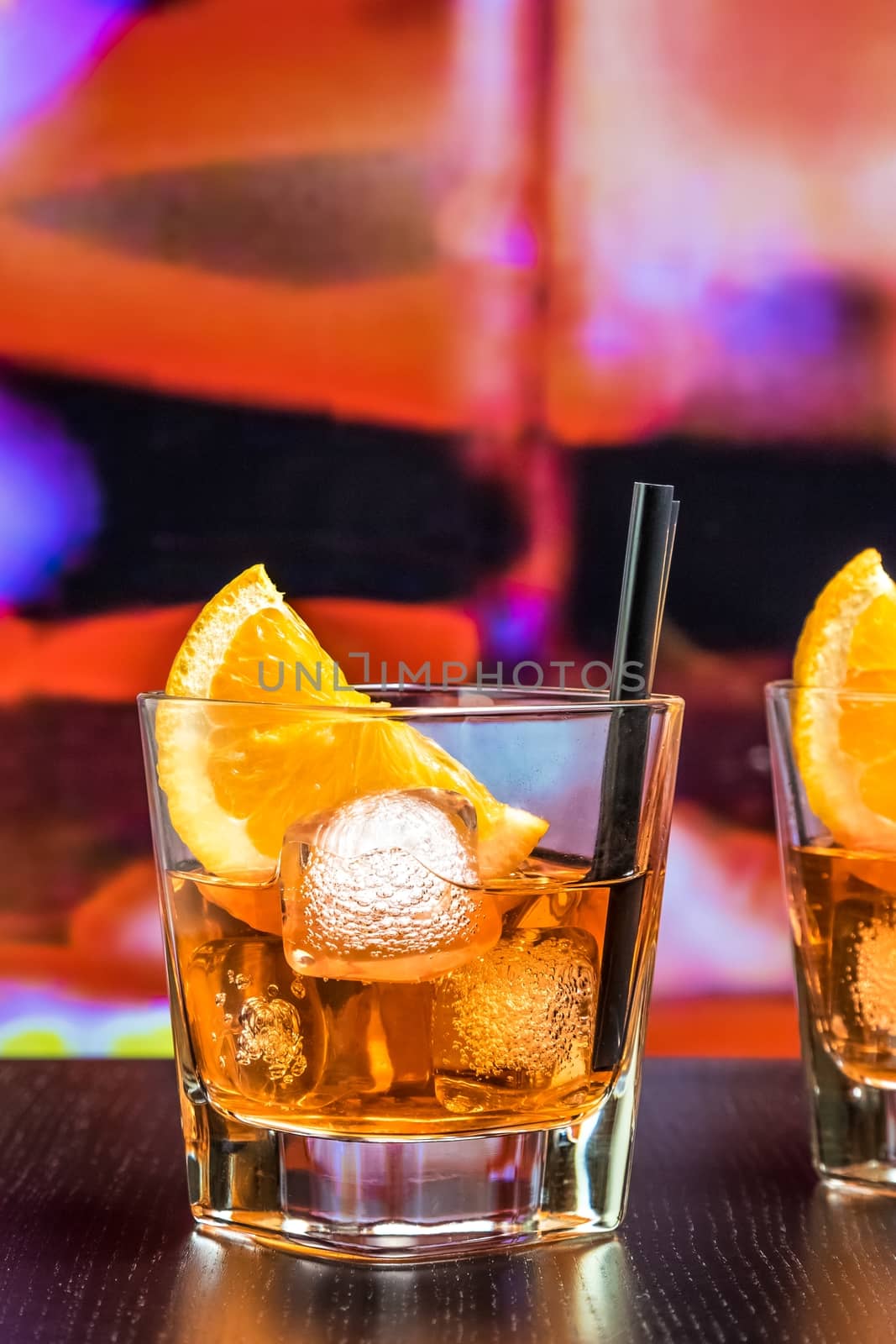 glasses of spritz aperitif aperol cocktail with orange slices and ice cubes on bar table, color pop atmosphere background, lounge bar concept