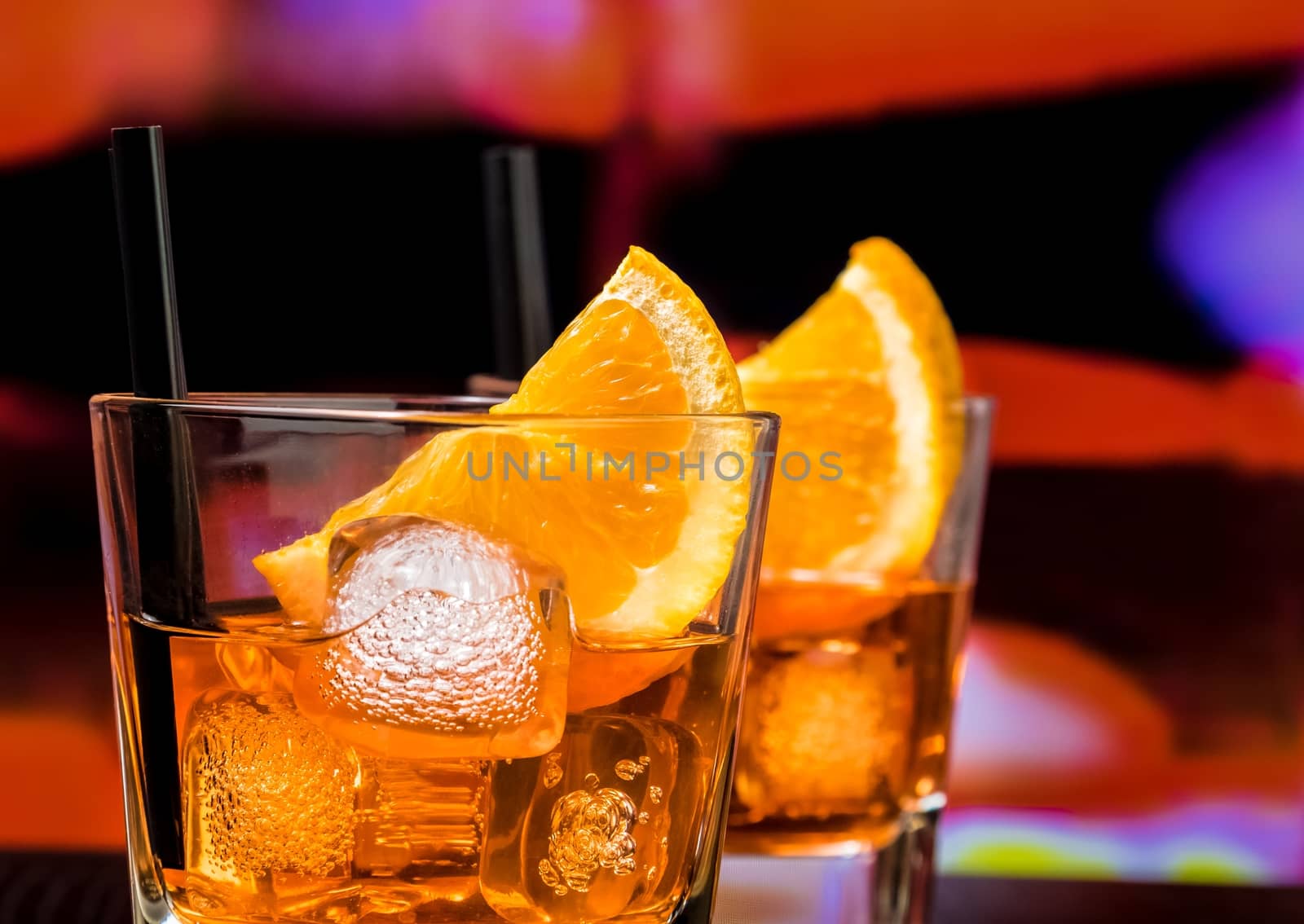detail of glasses of spritz aperitif aperol cocktail with orange slices and ice cubes on bar table, vintage atmosphere background, lounge bar concept