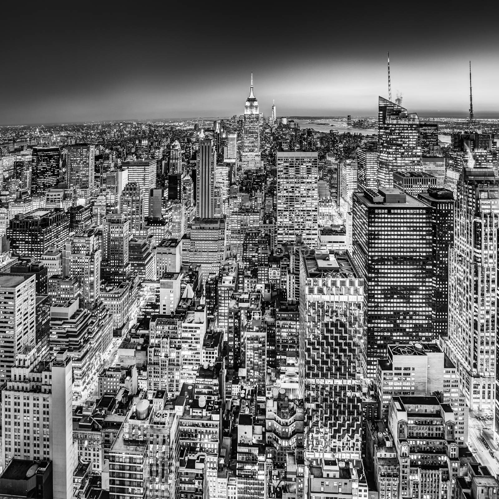 New York City. Manhattan downtown skyline with illuminated Empire State Building and skyscrapers at dusk. Black and white image. Square composition.