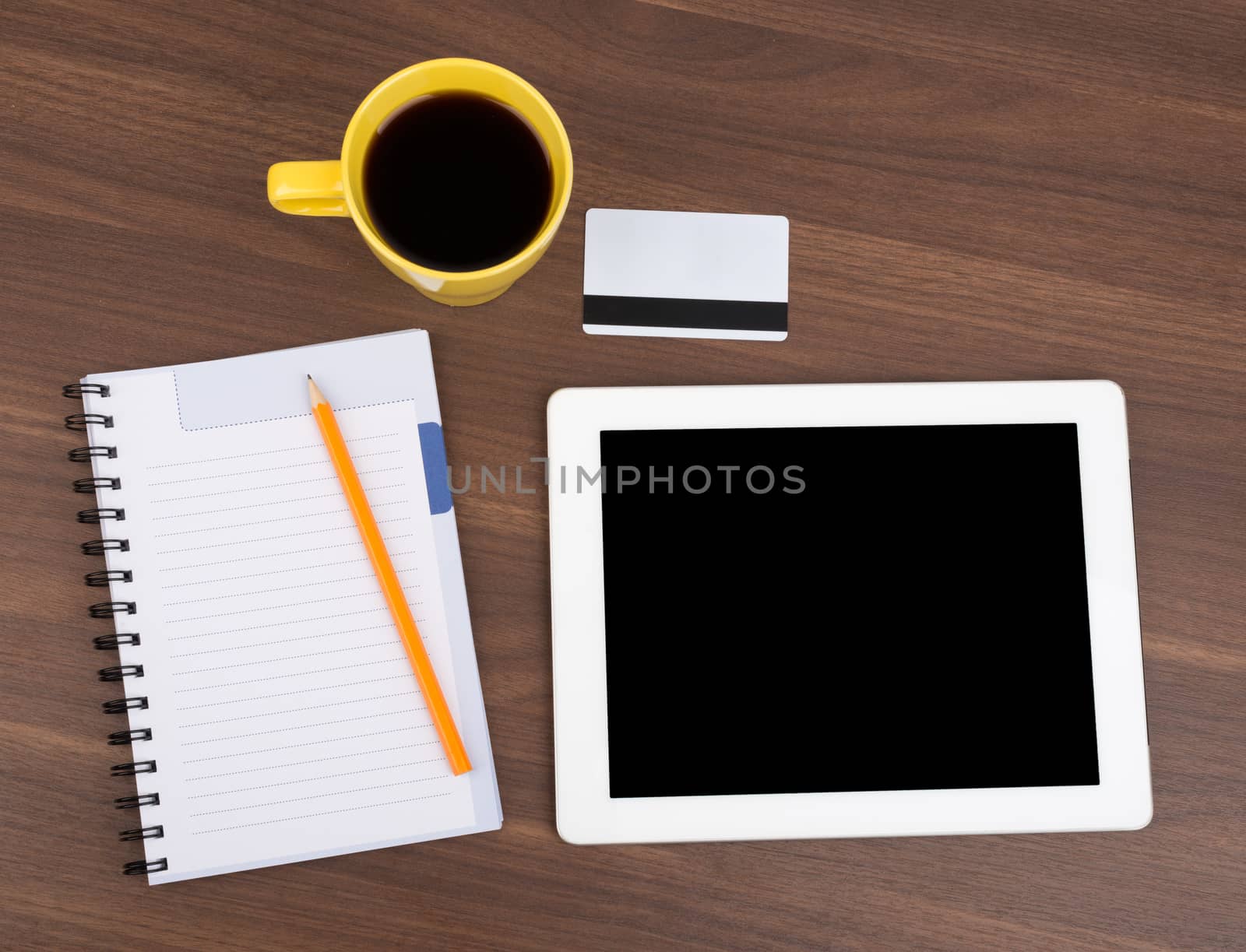 Blank copybook with tablet and empty card on wooden table