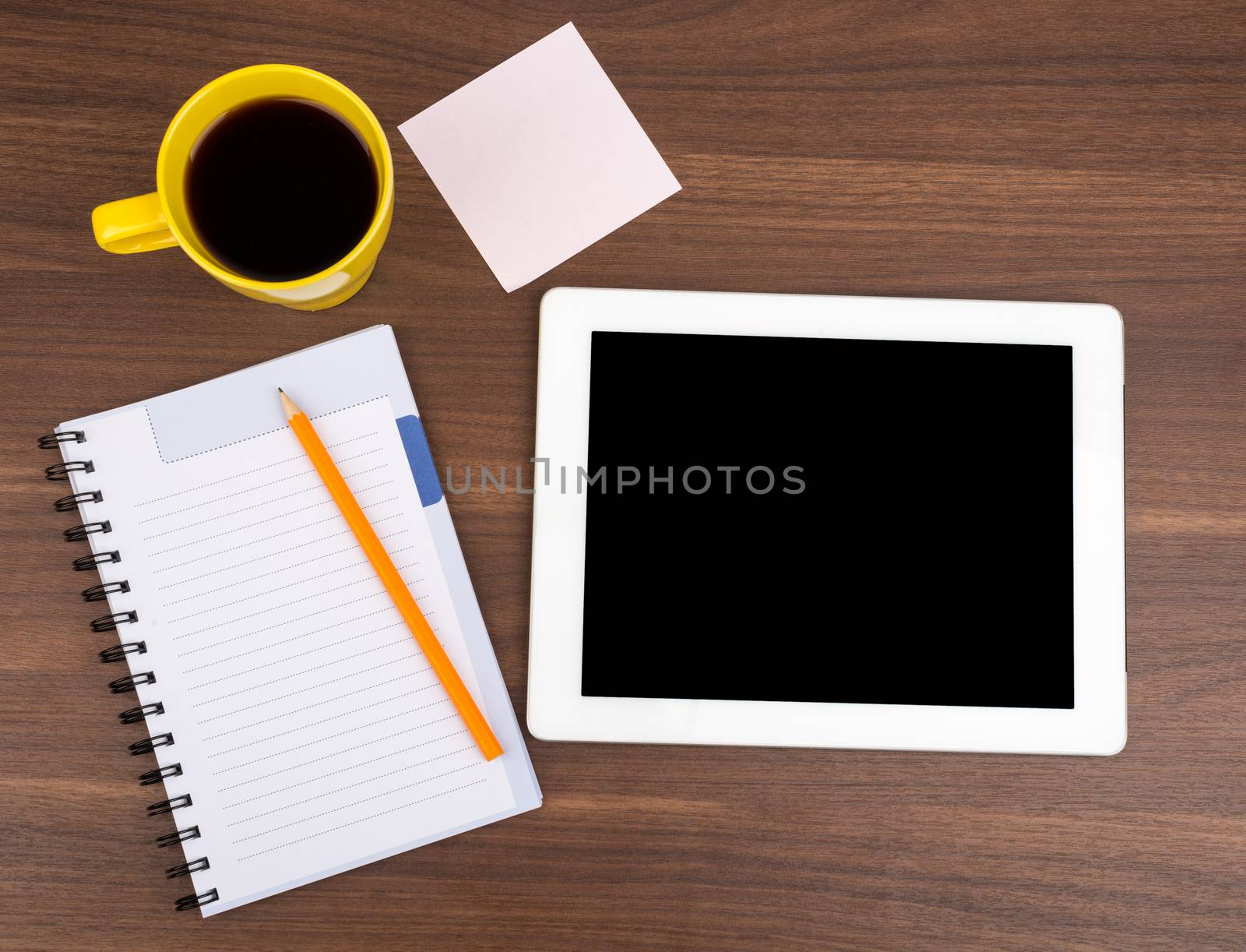 Blank copybook with tablet and sticker on wooden table