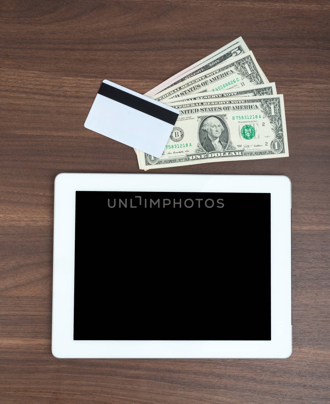 Tablet with money and credit card on wooden table