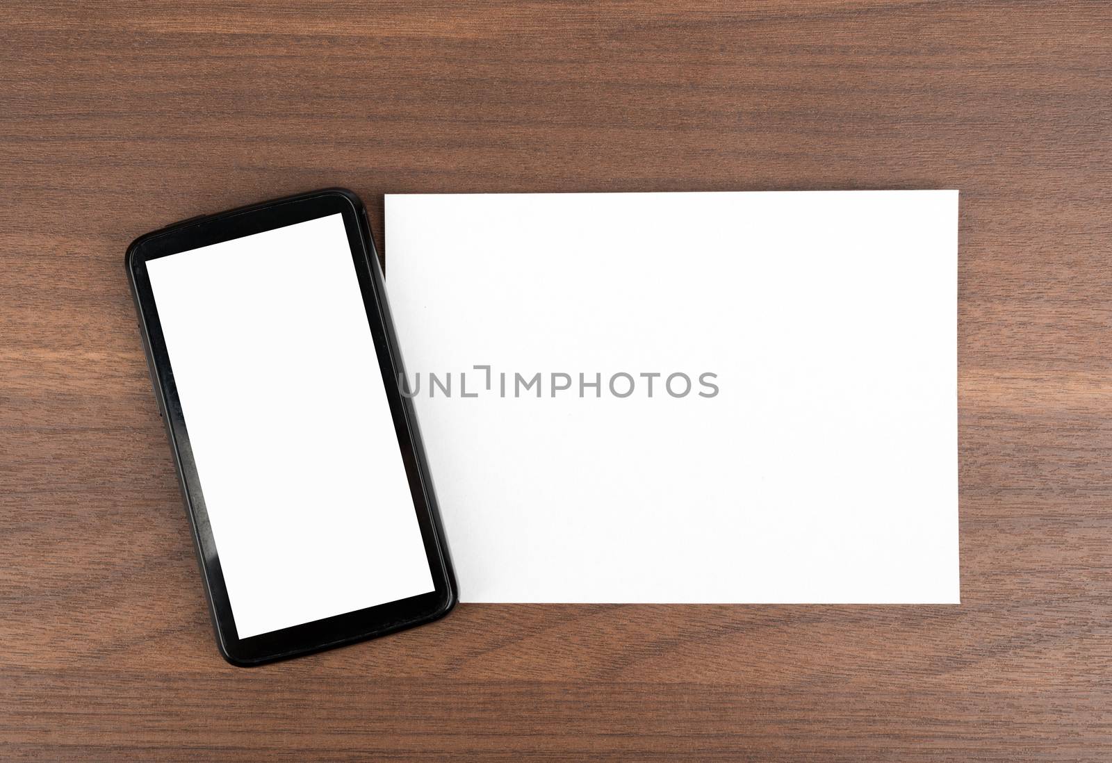 Blank card with smartphone on wooden table