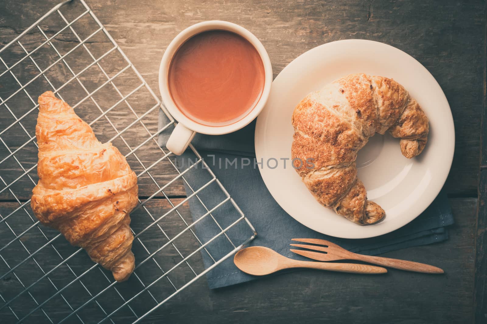 Butter croissant and whole wheat croissant with a cup of hot chocolate on wood table in morning time with film filter effect