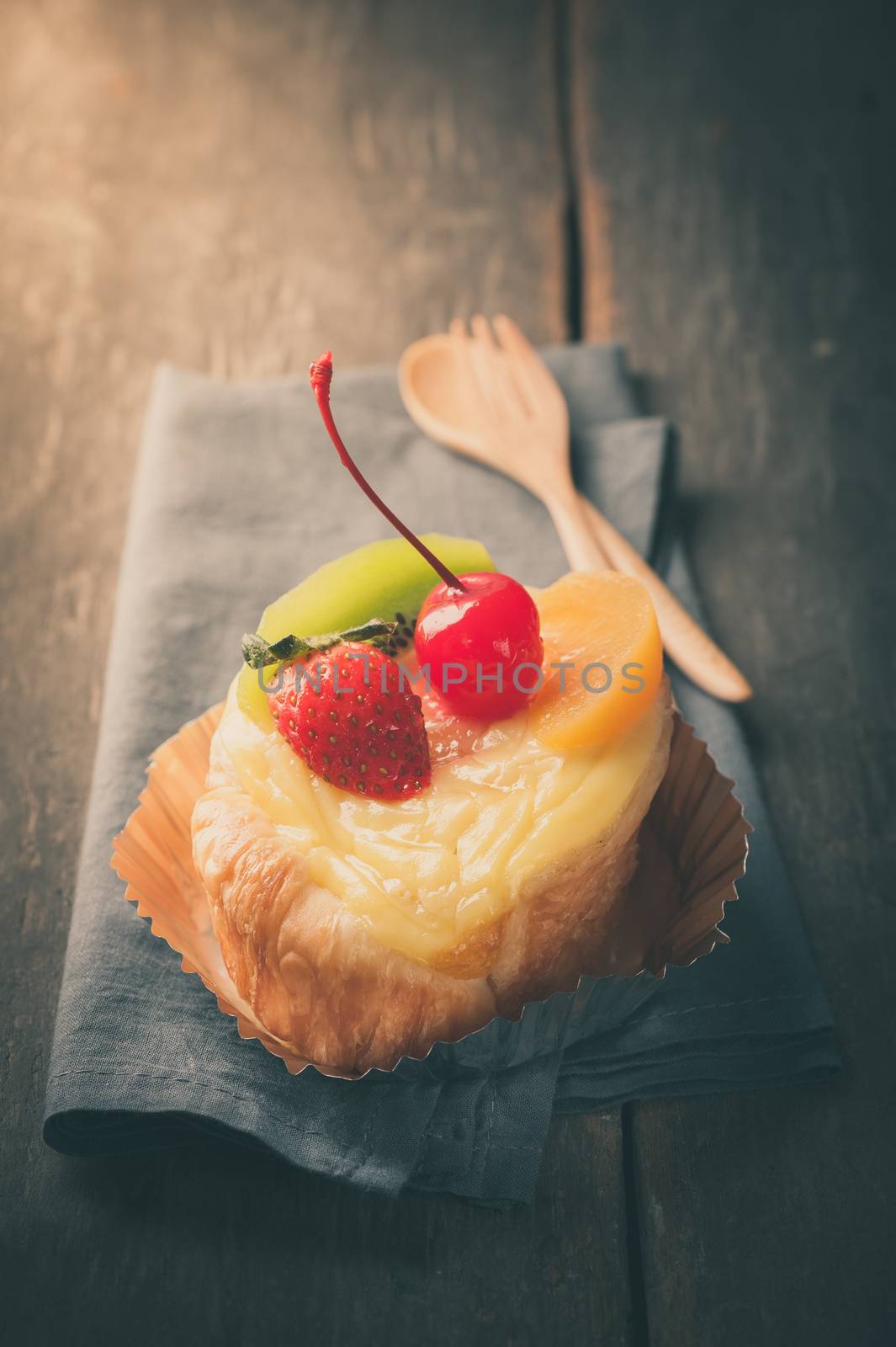 Fruit danish pastry on wood table in morning time with film filter effect