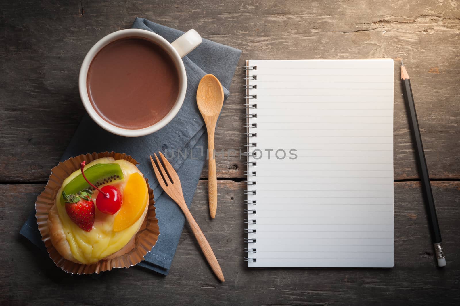 Fruit danish pastry with hot chocolate and opened notebook with blank area for text or message on wood table in morning time