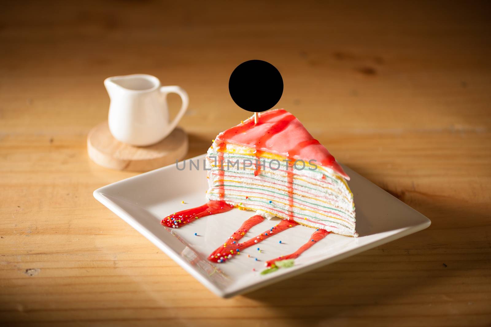 Rainbow crepe cake with black label on top in afternoon low key scene
