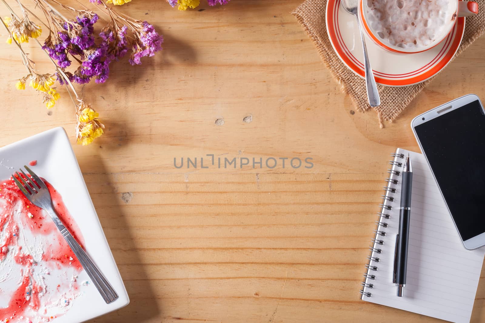 Wood table background with blank area for text or message, opened notebook, pen and a cup of hot coffee as frame in afternoon time