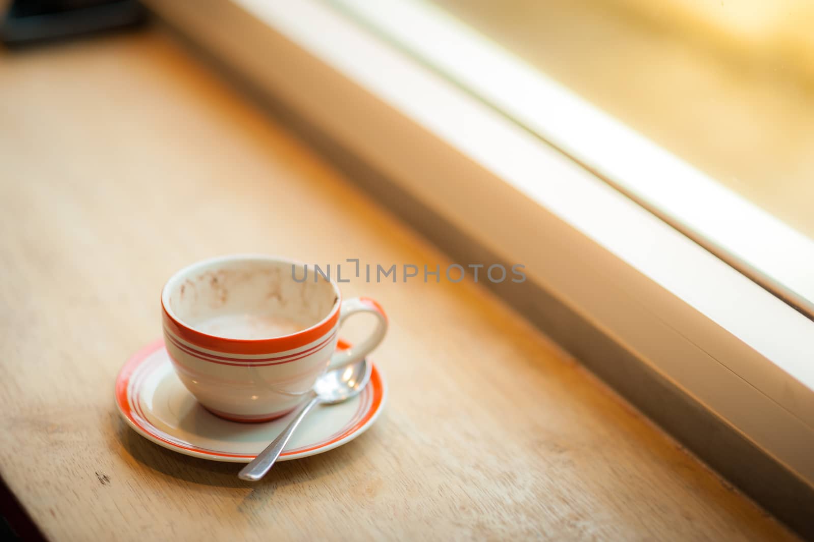 Coffee cup on wood bar beside window at coffee shop in afternoon time